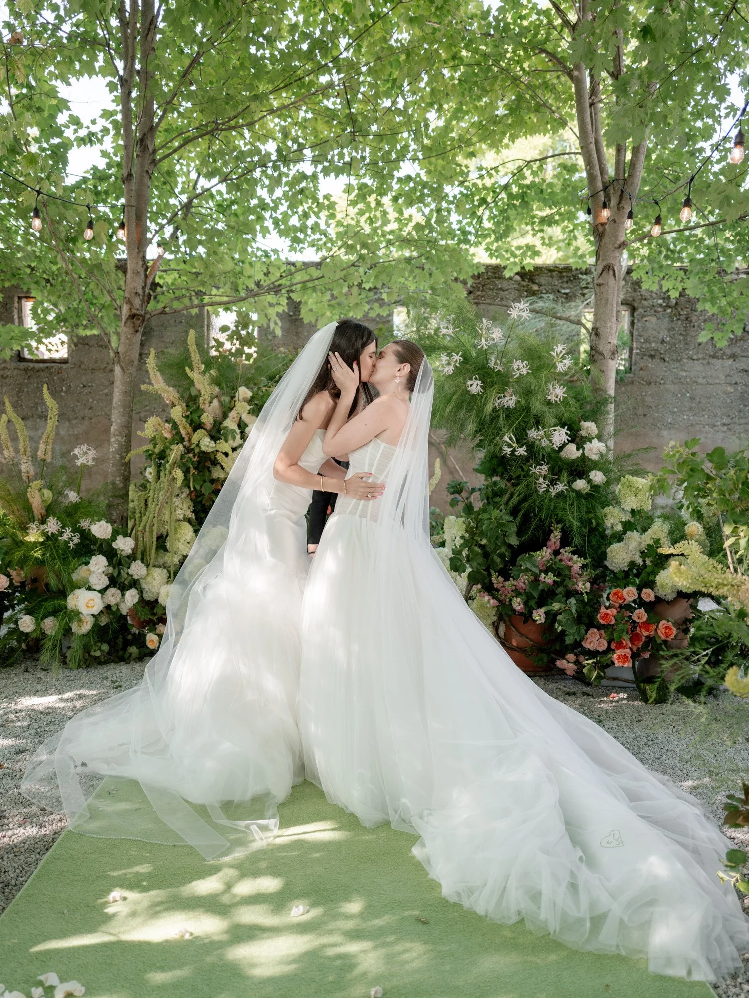The couple’s first kiss beneath dappled light and floral greenery at Valley Rock Inn in Sloatsburg, photographed by Jenny Fu.
