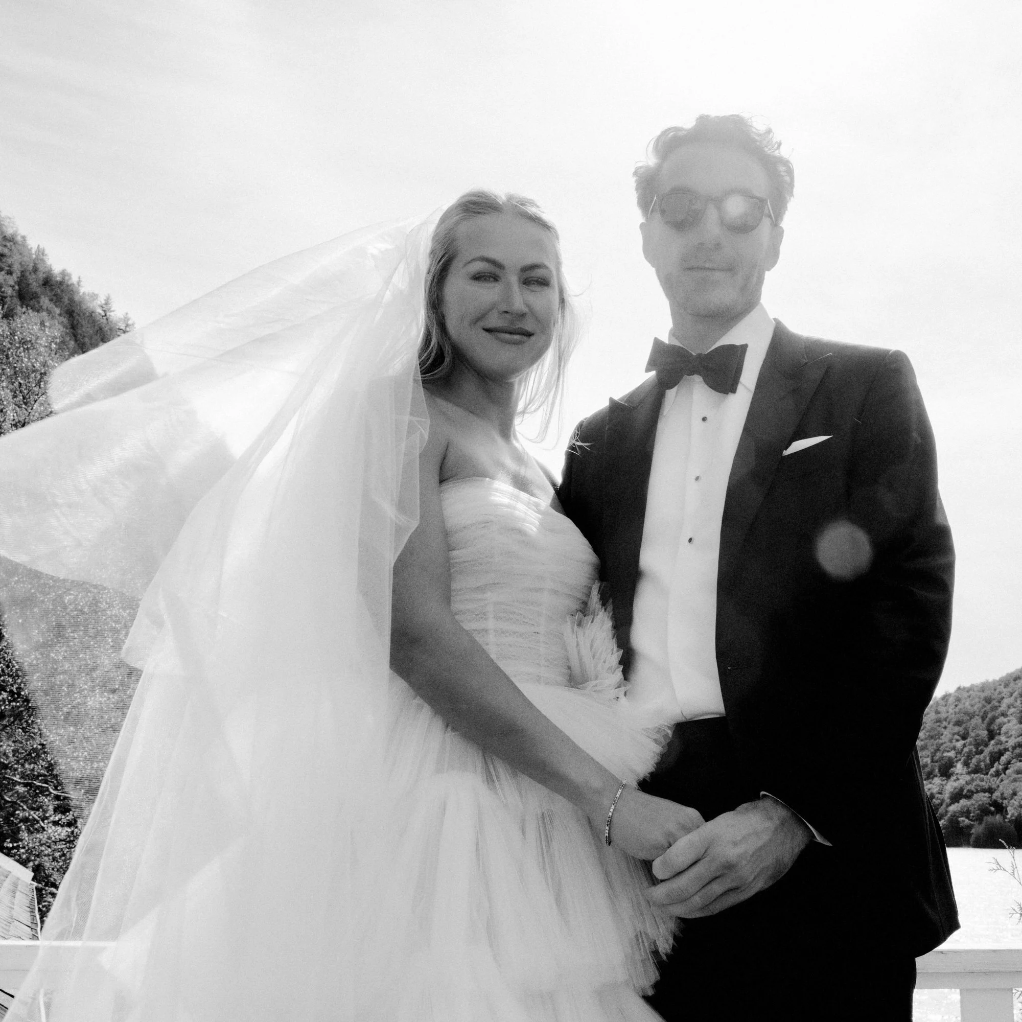 Black and white wedding portrait of bride and groom standing together on lakeside deck at The Ausable Club in the Adirondacks