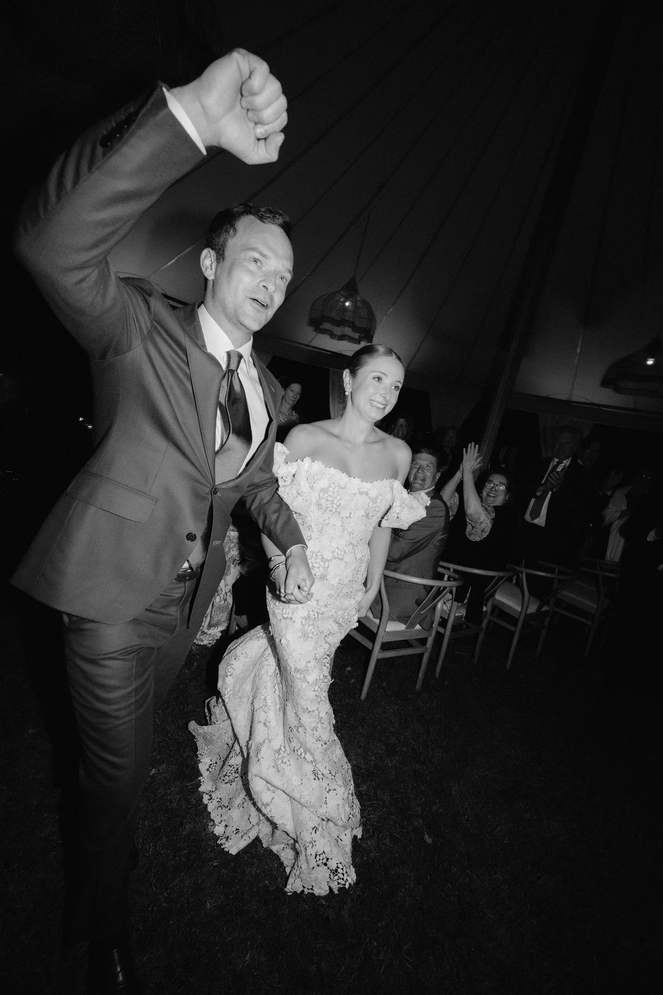 Bride and groom making a jubilant entrance at night, captured in black and white at Troutbeck in Amenia, New York, photographed by Jenny Fu.