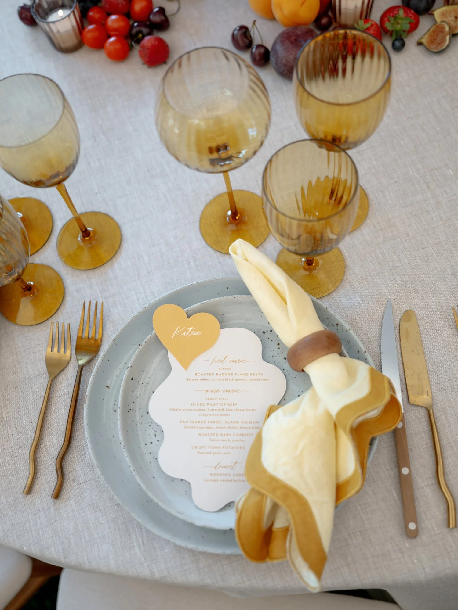 Editorial detail of a scalloped menu, yellow napkin, and amber glassware at the wedding dinner table at Valley Rock Inn in Sloatsburg, photographed by Jenny Fu.