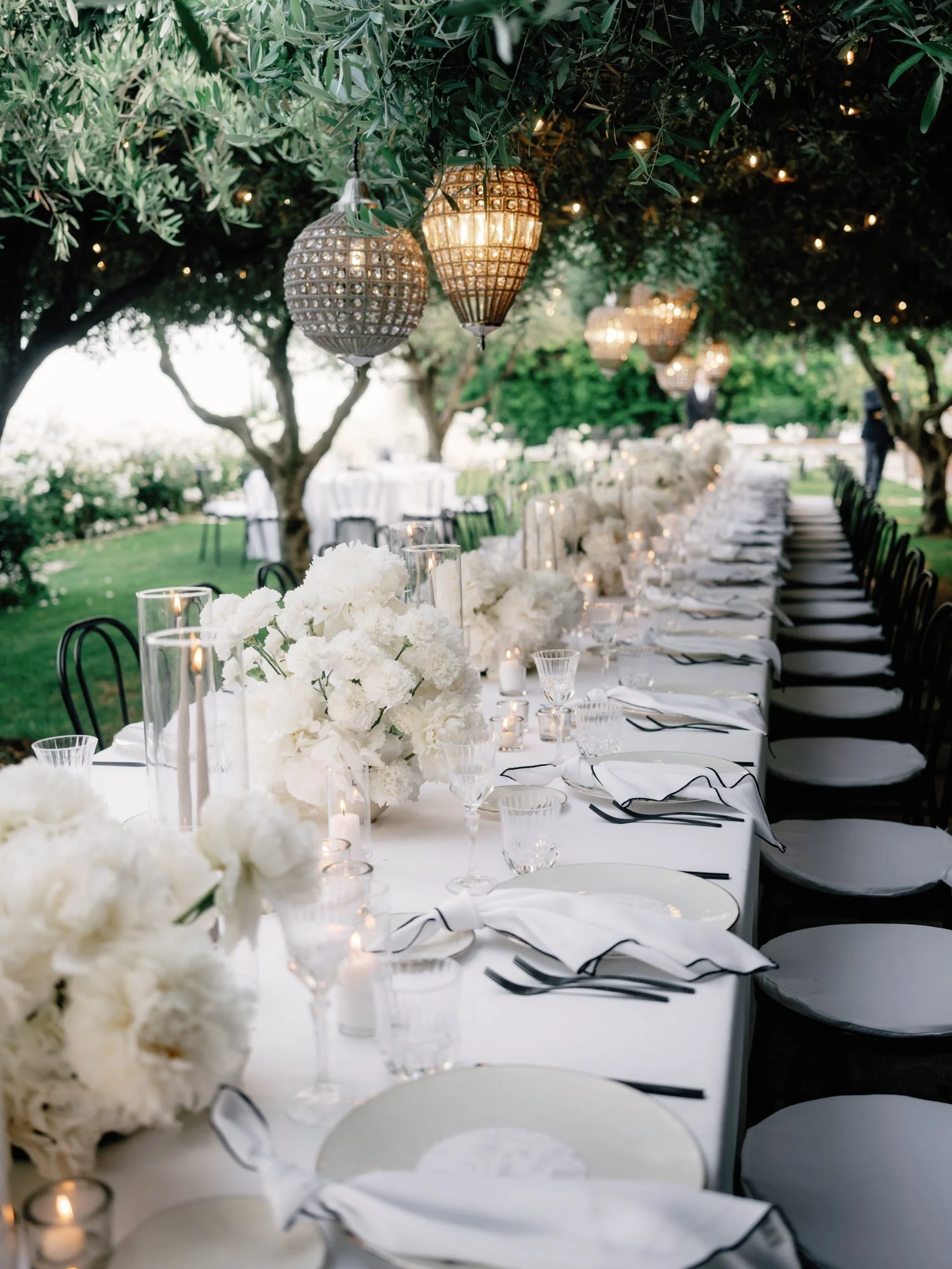White floral arrangements in glass vases set on a terrace table with mountain views at Caruso, A Belmond Hotel in Ravello, Italy, photographed by Jenny Fu.