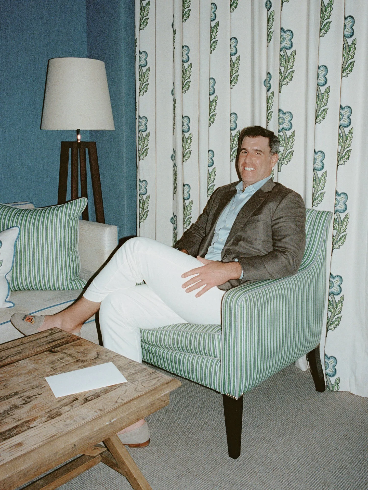 Groom relaxing in a green-striped chair during wedding morning preparations at Crosby Street Hotel in Soho, photographed by Jenny Fu.