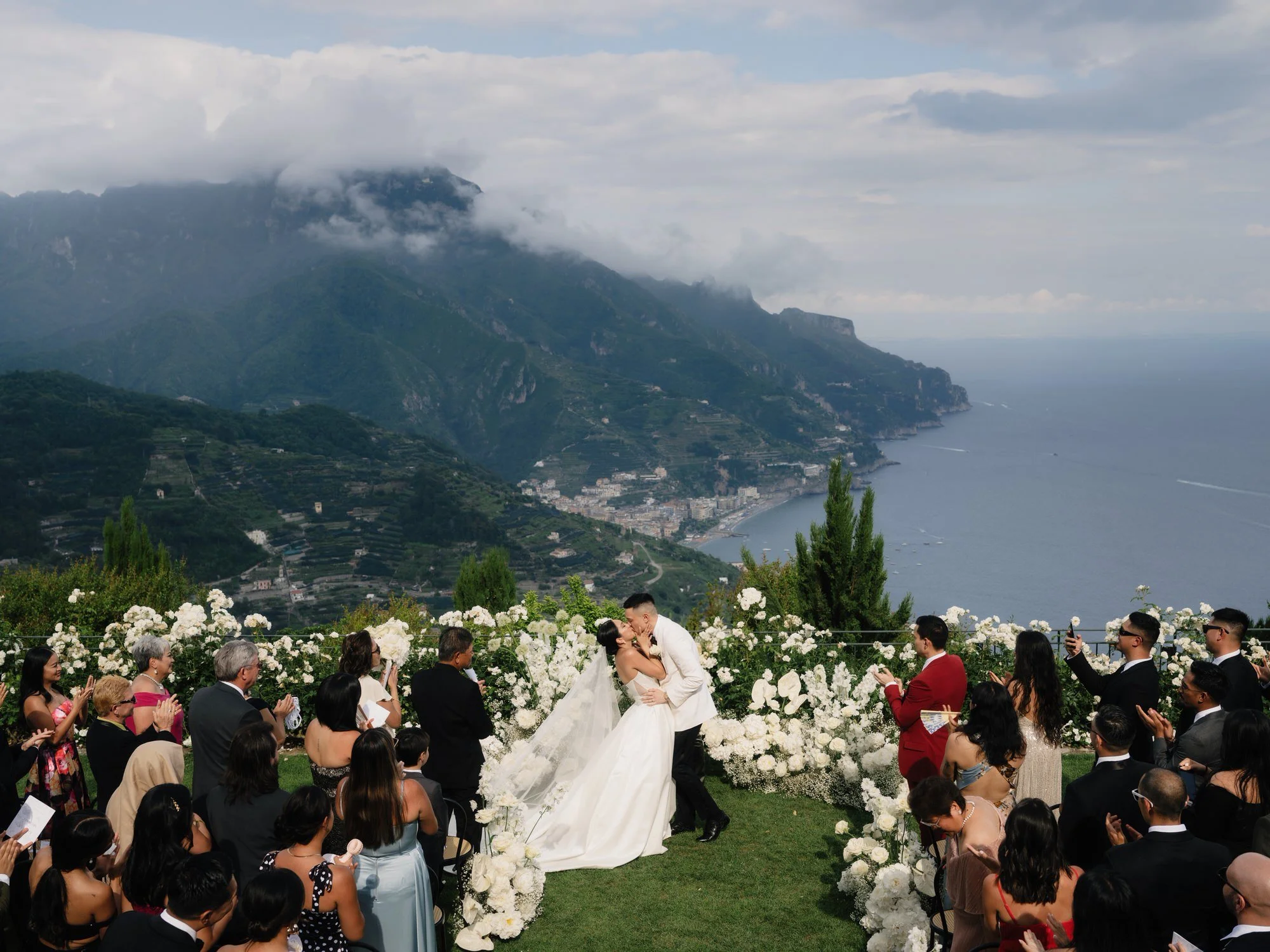 Bride and groom kissing at the ceremony altar overlooking the Amalfi Coast at Caruso, A Belmond Hotel in Ravello, Italy, photographed by Jenny Fu.