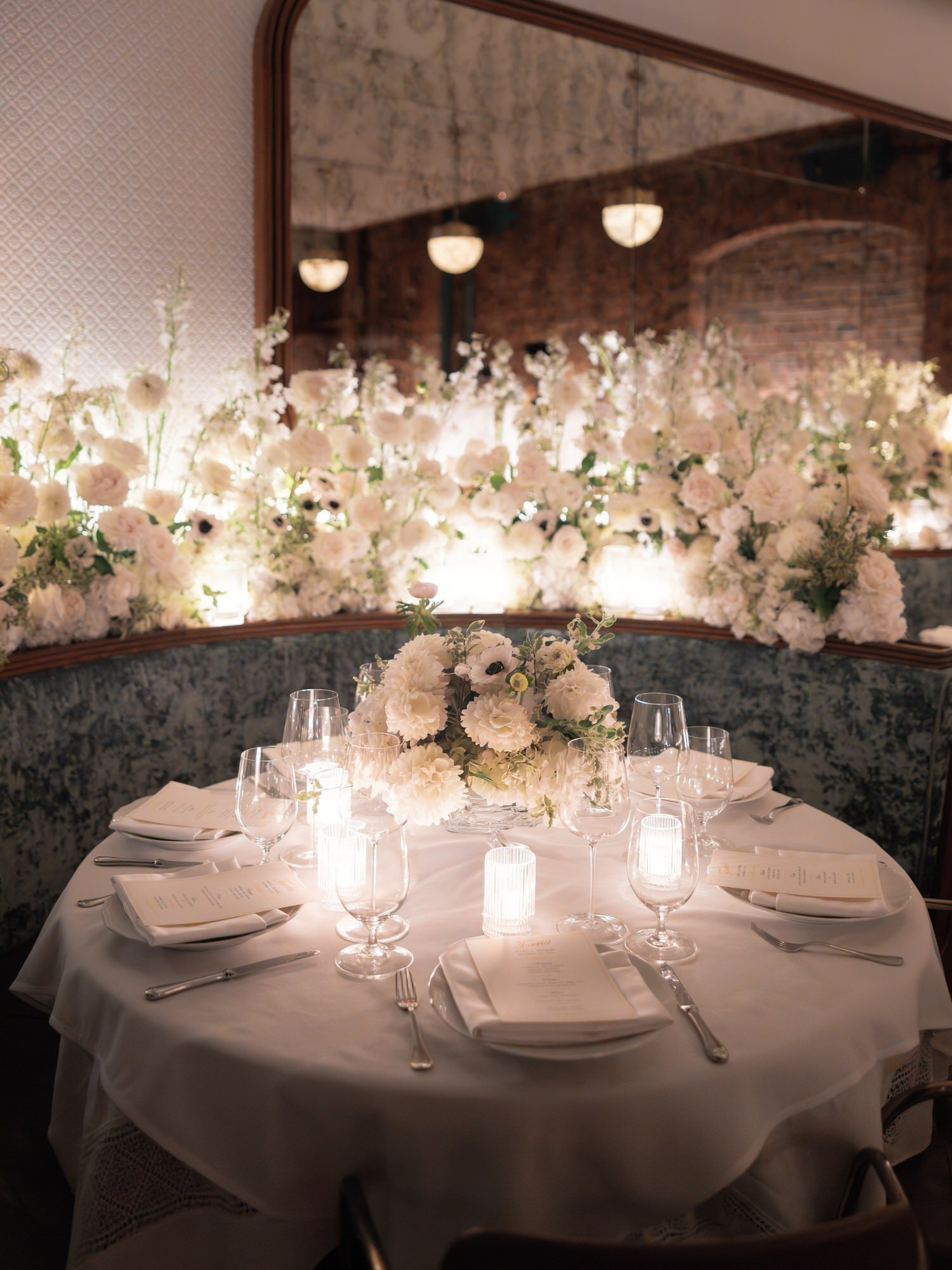 Intimate candlelit dinner table surrounded by white floral arrangements at Torrisi in Manhattan, photographed by Jenny Fu.