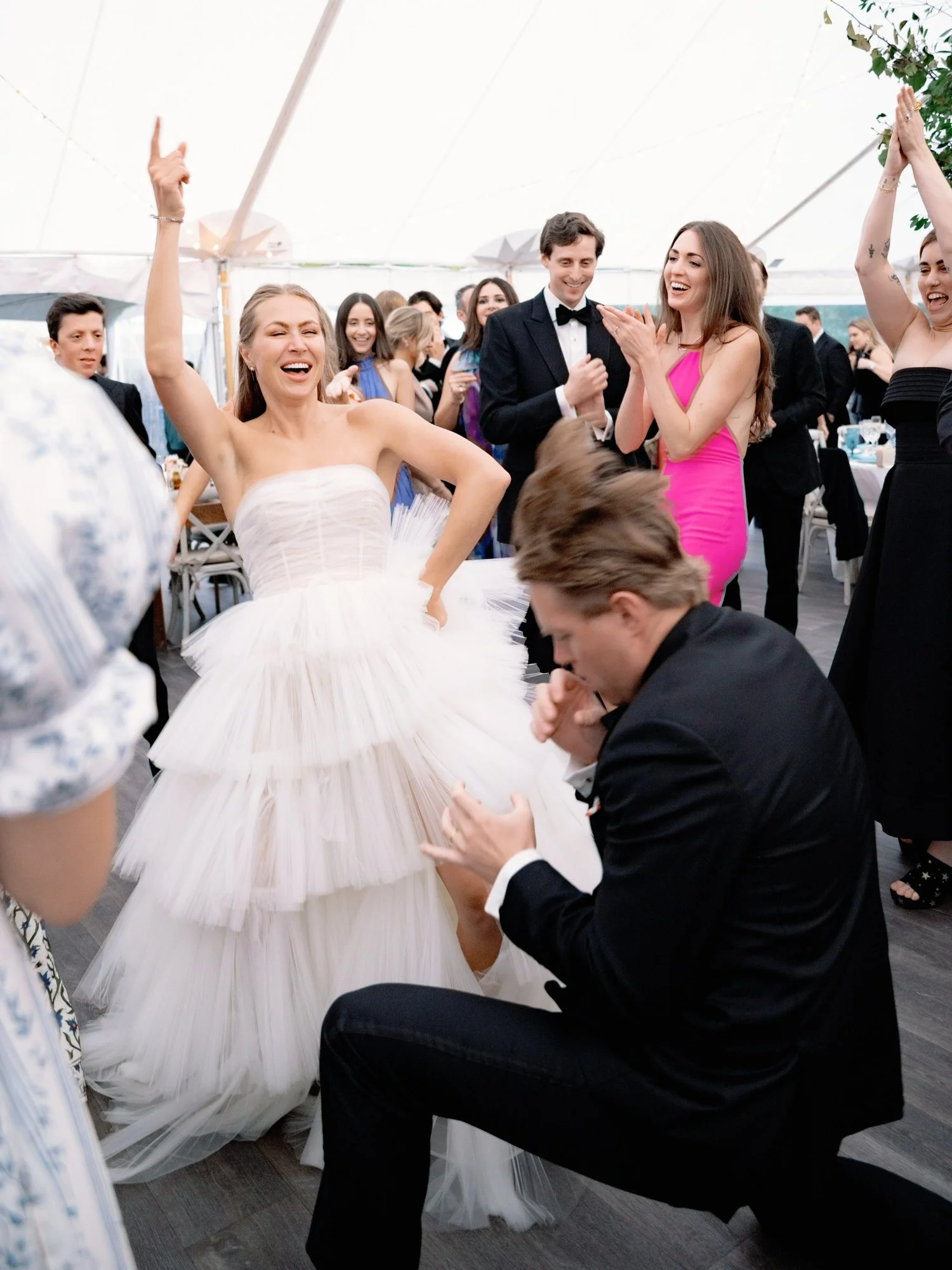 Bride laughing and dancing energetically with friends during wedding reception at Ausable Club