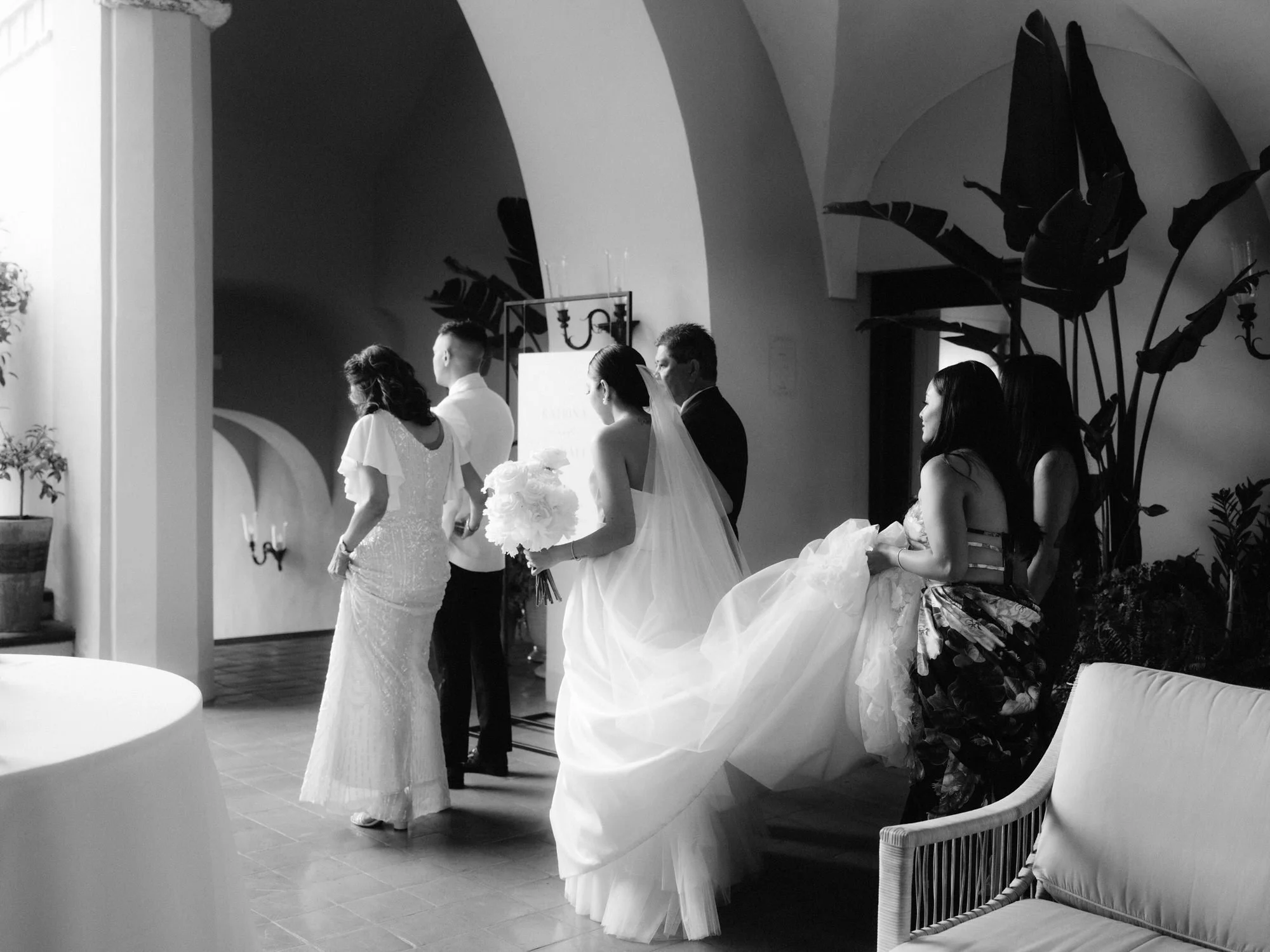 Bride walking with her family through the arches of Caruso, A Belmond Hotel before the ceremony in Ravello, Italy, photographed by Jenny Fu.