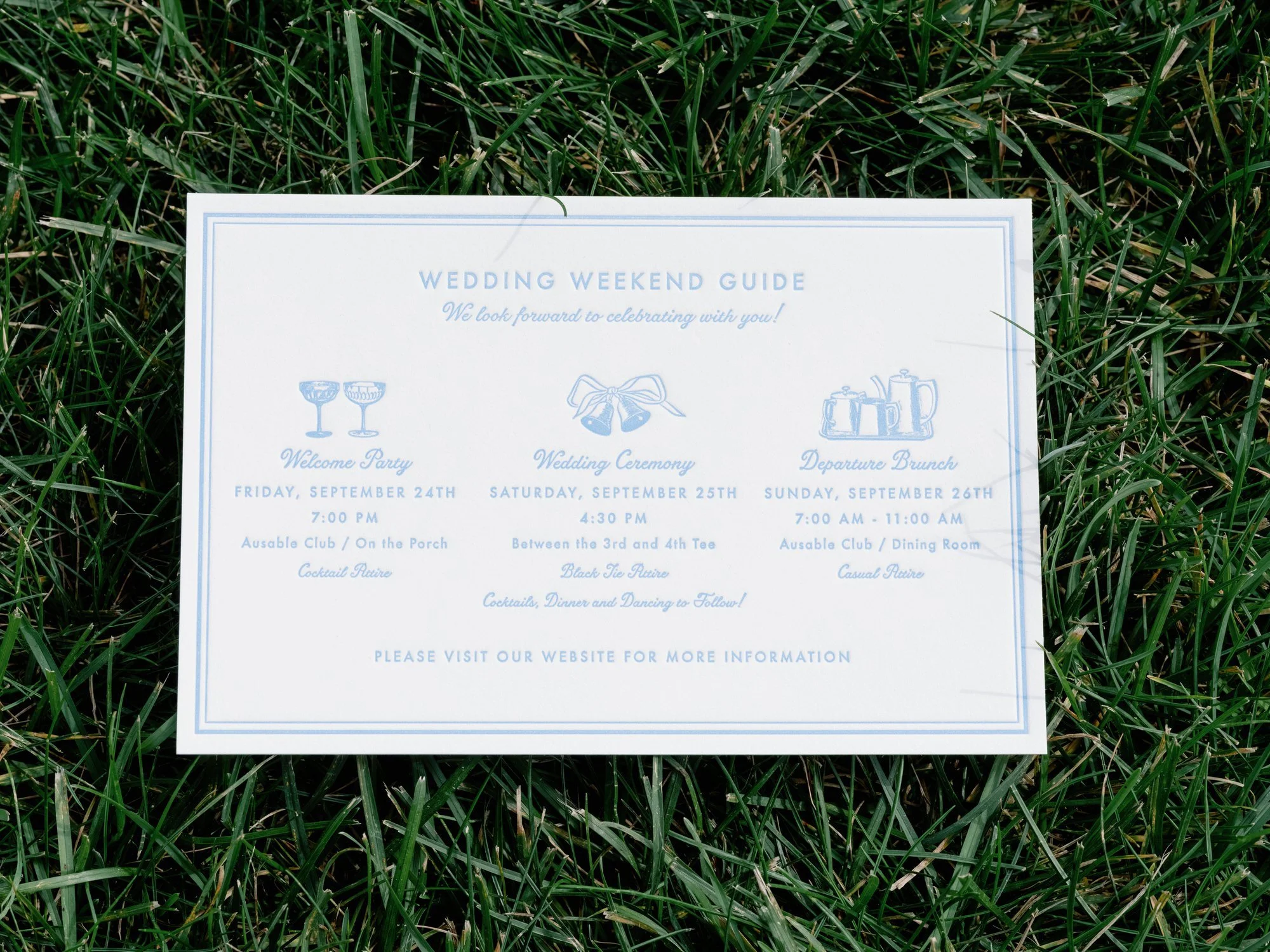 Detail photo of Olivia and Jack’s wedding weekend guide card on the grass at the Ausable Club in the Adirondacks
