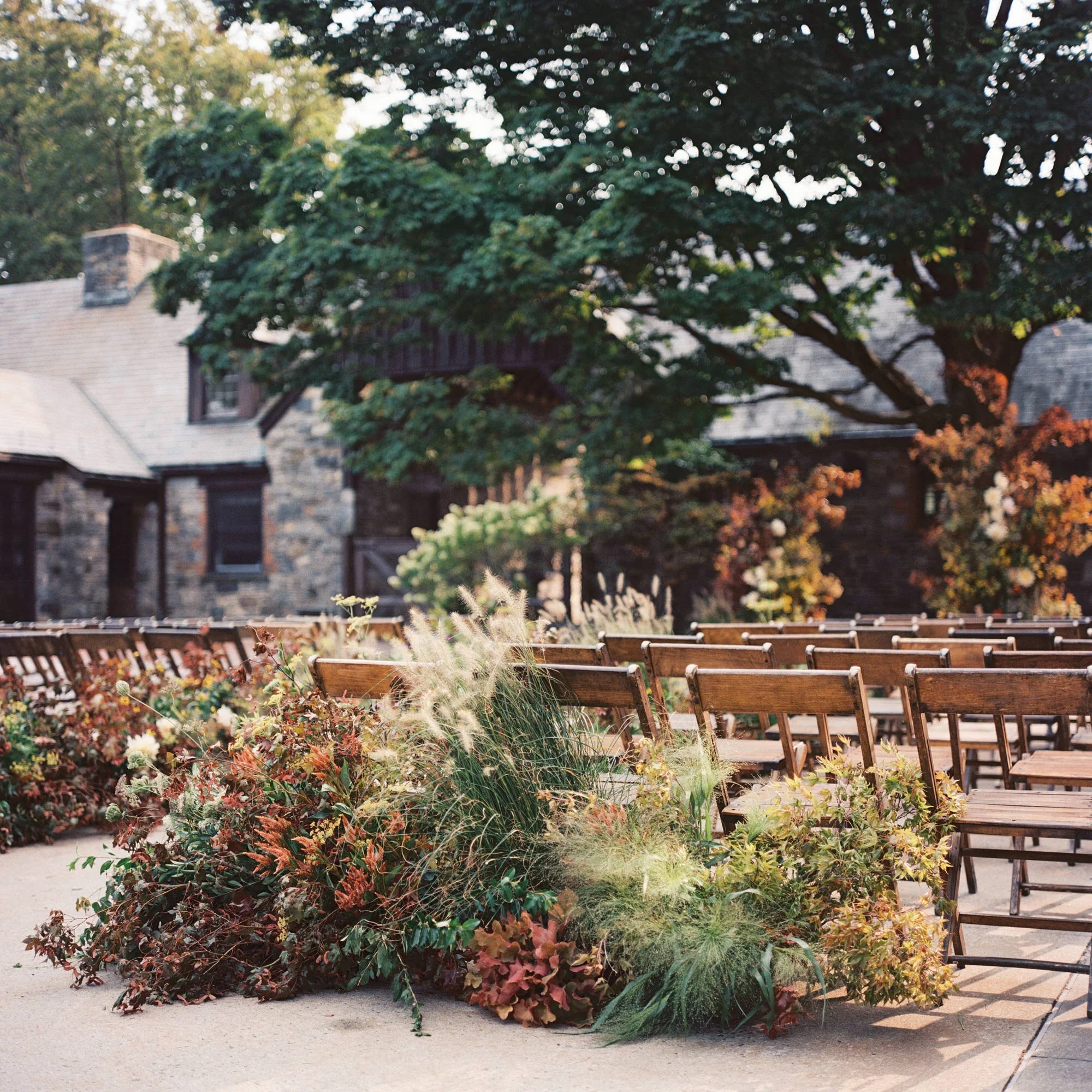 Late-afternoon view of the ceremony garden with wooden chairs and lush aisle plantings on film at Blue Hill at Stone Barns, photographed by Jenny Fu.
