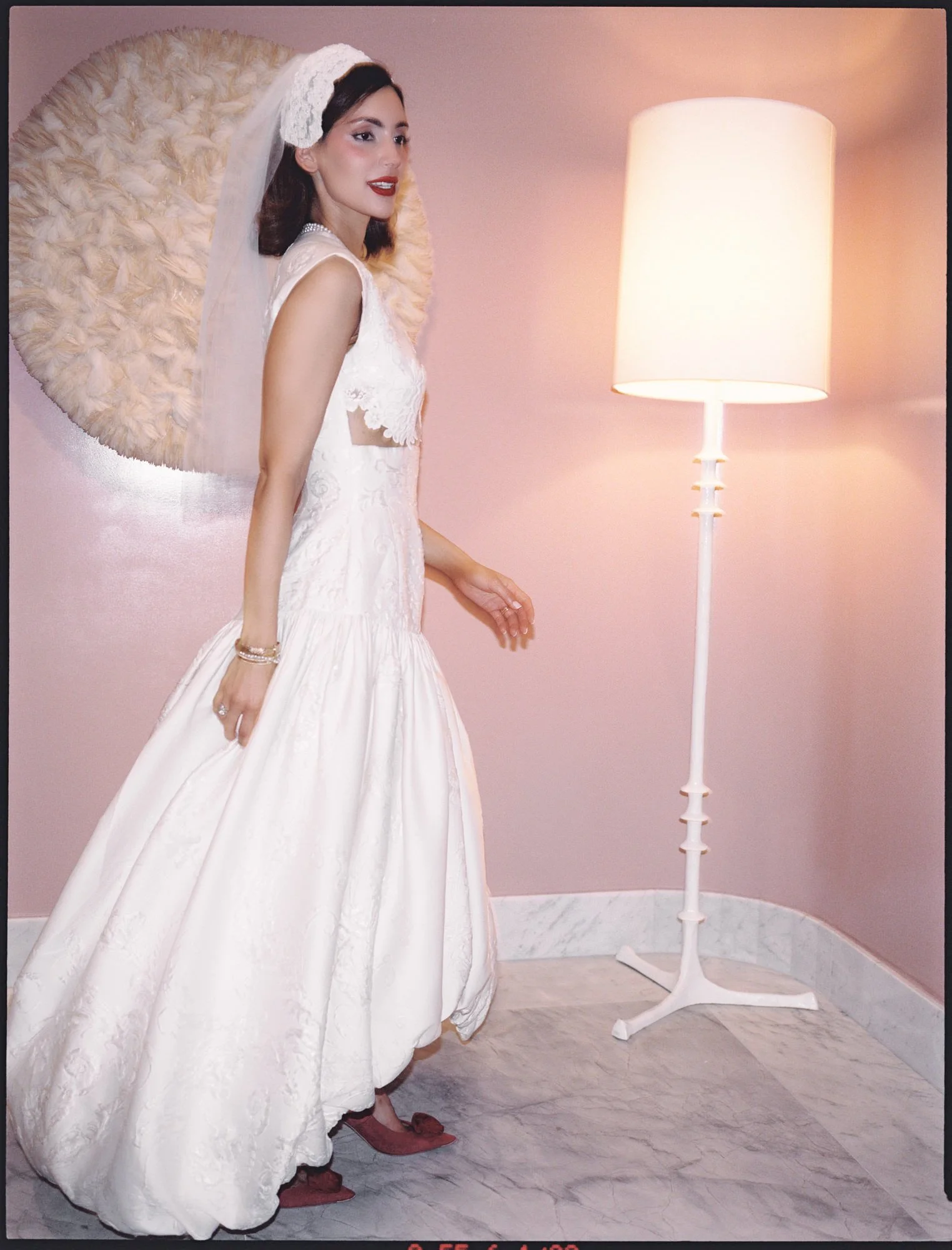 Bride in a drop-waist gown and veil posing beside a floor lamp in a blush suite at the Waldorf Astoria New York, photographed by Jenny Fu.