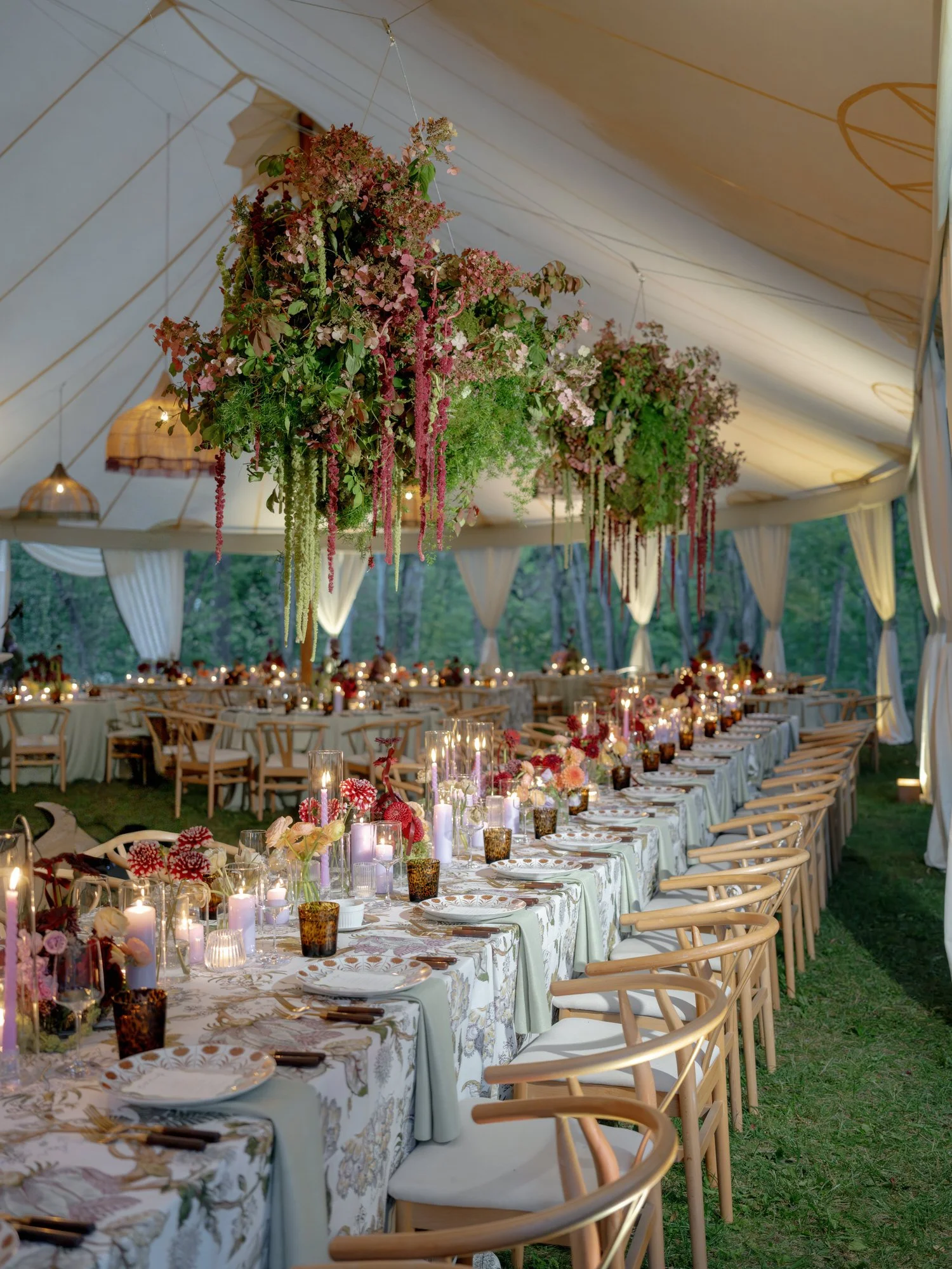 Candlelit long table set for dinner under suspended floral arrangements at Troutbeck in Amenia, New York, photographed by Jenny Fu.