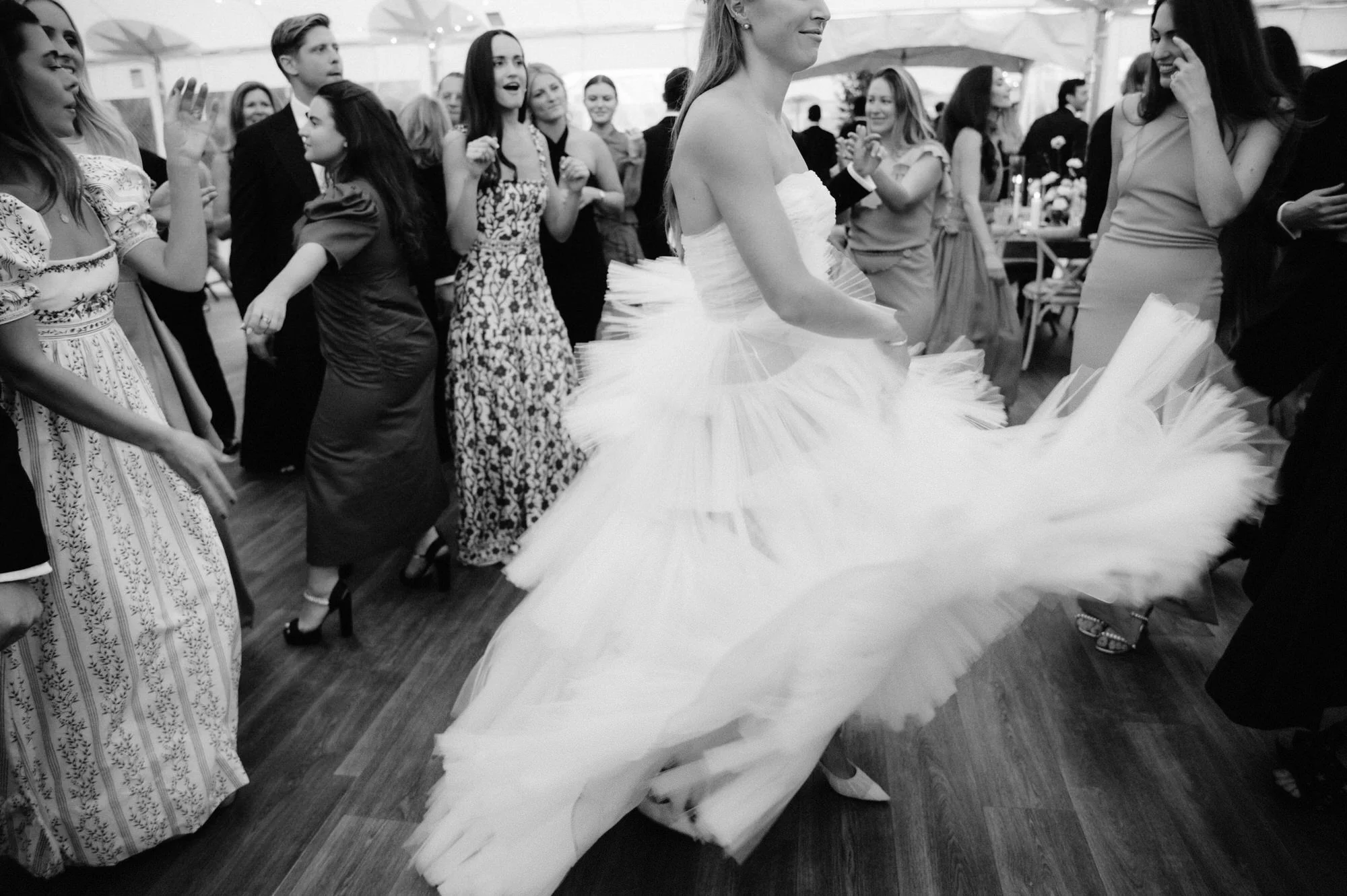 Bride twirling on the dance floor surrounded by cheering guests during reception at Ausable Club