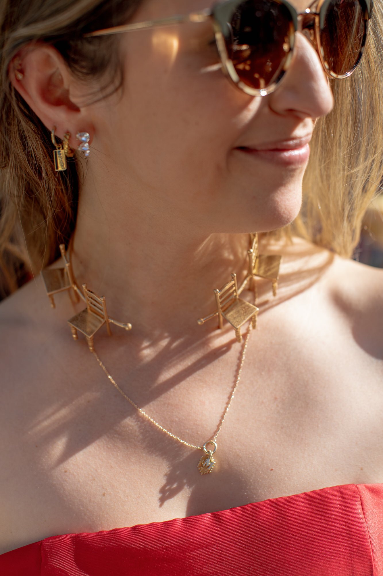 Close-up of guest wearing a unique gold chair necklace and sunglasses in the afternoon light at Valley Rock Inn in Sloatsburg, photographed by Jenny Fu.
