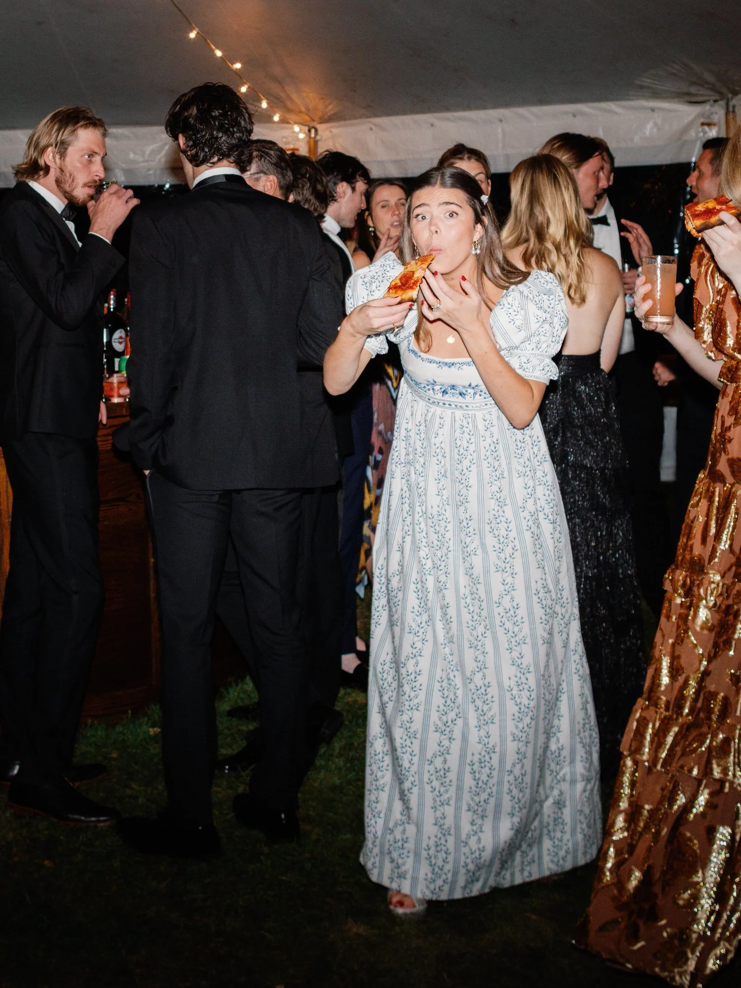 A guest laughs while enjoying a late-night slice of pizza under the reception tent at the Ausable Club in the Adirondacks