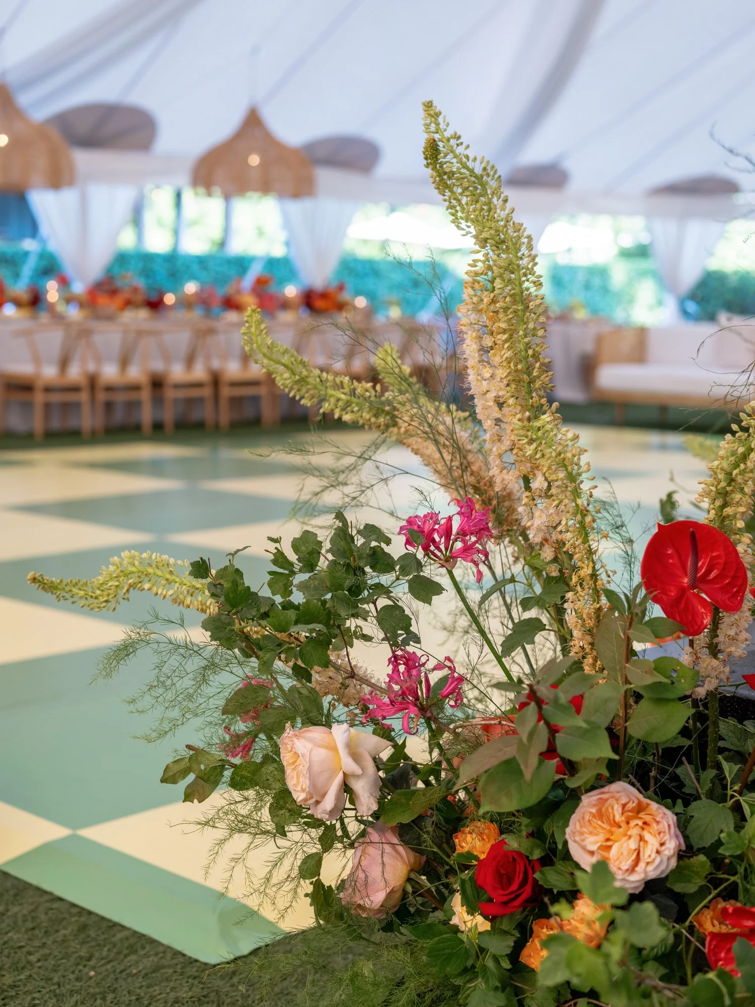 Bright floral arrangement near the checkered dance floor inside the tented reception at Valley Rock Inn in Sloatsburg, photographed by Jenny Fu.