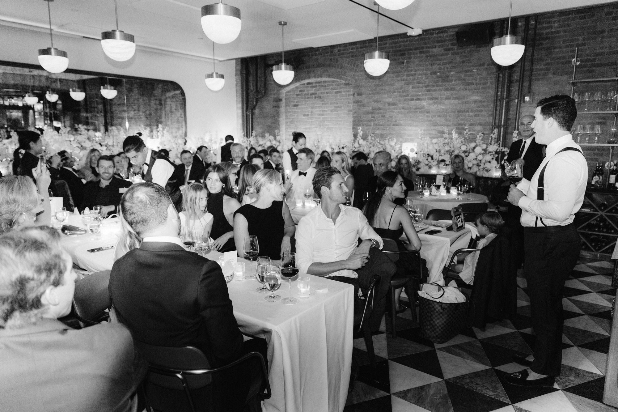 Guests listening attentively during heartfelt wedding speeches at Torrisi in Manhattan, photographed by Jenny Fu.