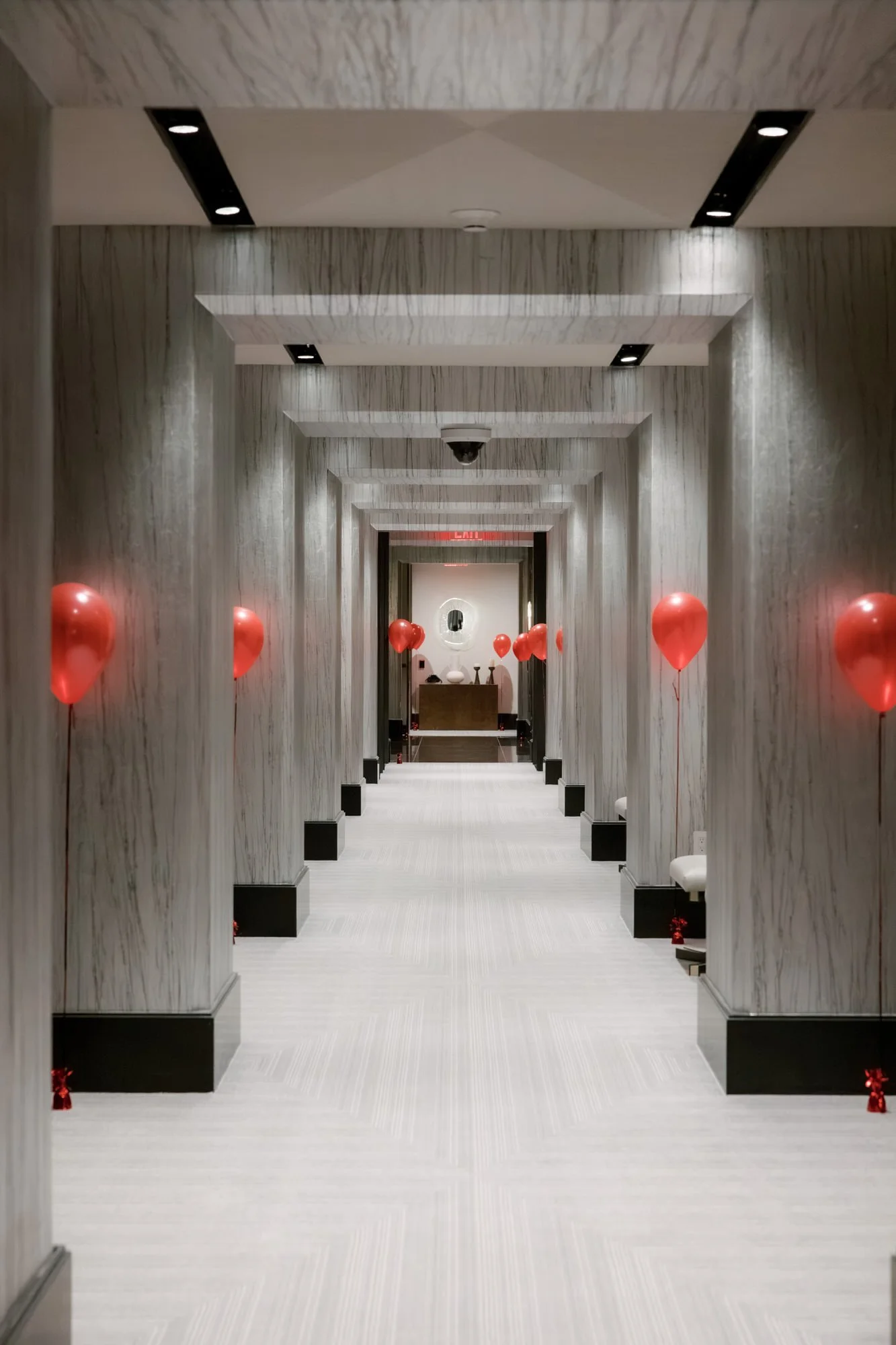 Hotel corridor lined with red balloons at the Waldorf Astoria New York, photographed by Jenny Fu.