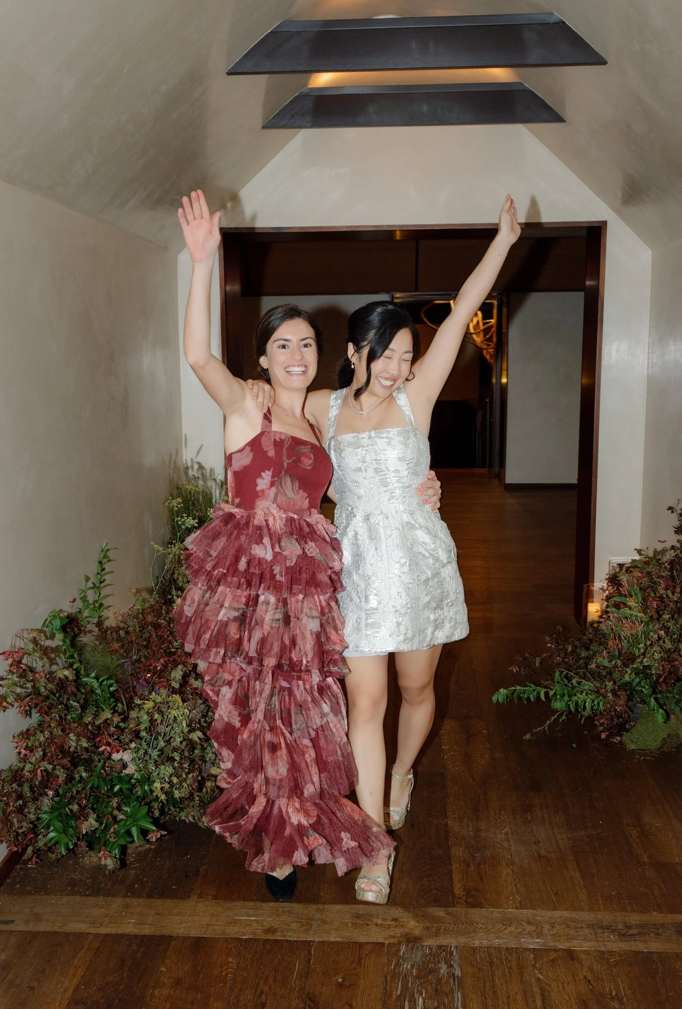 Bride and bridesmaid cheering arm in arm in the hallway before the party at Blue Hill at Stone Barns, photographed by Jenny Fu.