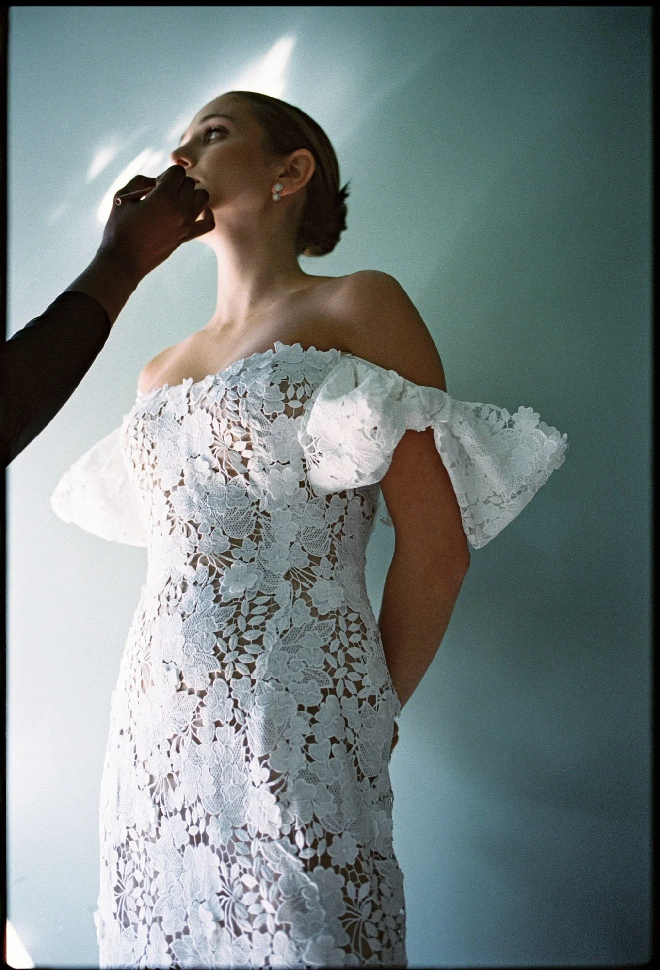 Makeup artist applying final touches to the bride in natural light at Troutbeck in Amenia, photographed by Jenny Fu.