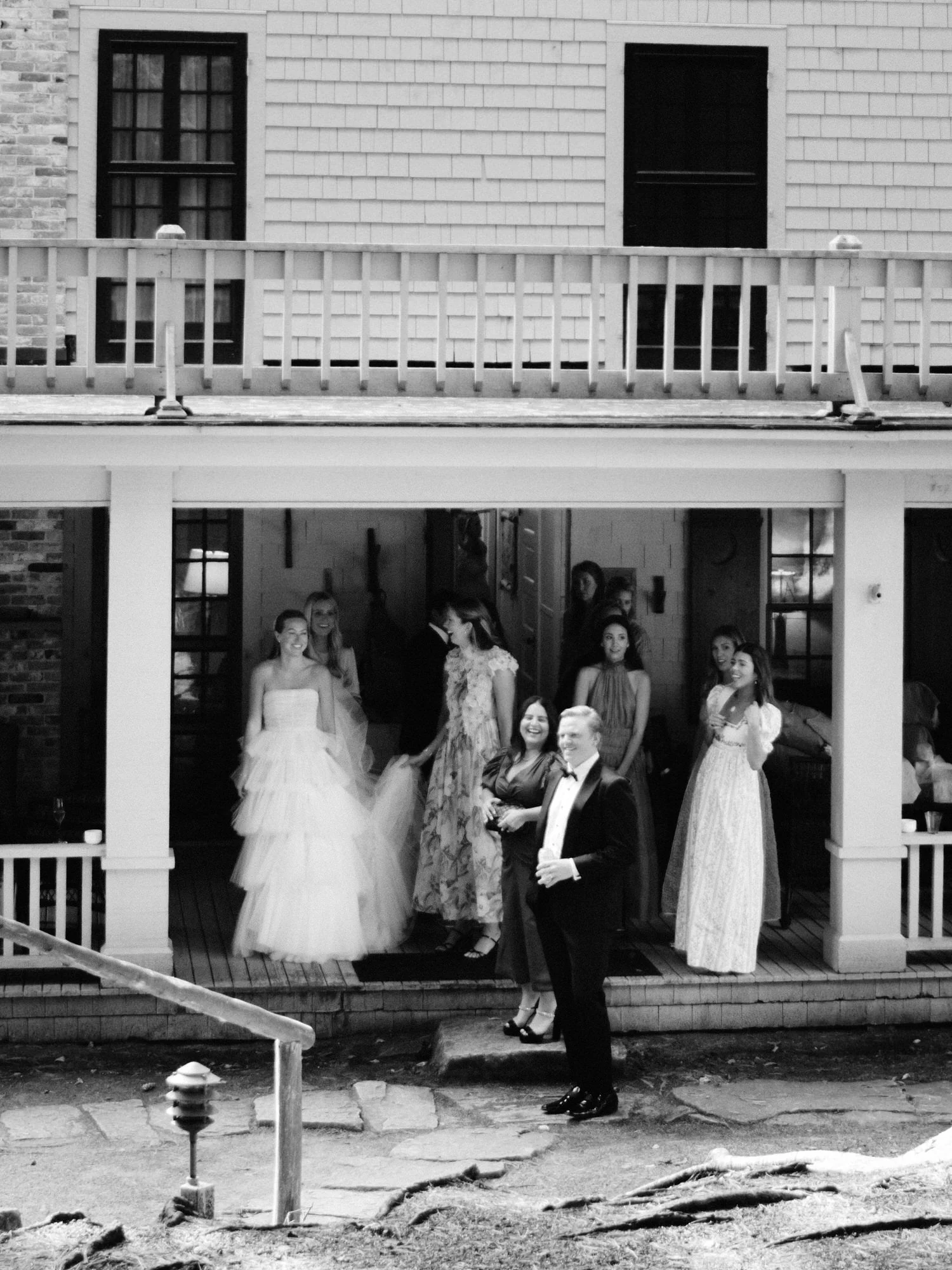 Wedding guests in colorful gowns gathered on porch steps of The Ausable Club in the Adirondacks
