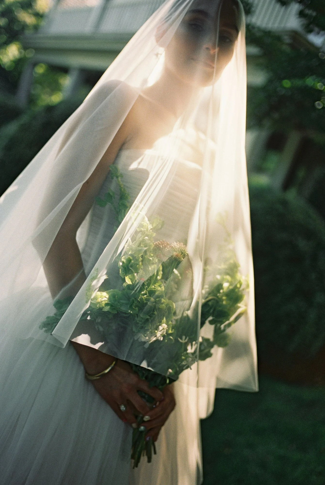 Bride under sheer veil with green bouquet, glowing in sunlight at Valley Rock Inn in the Hudson Valley shot on film