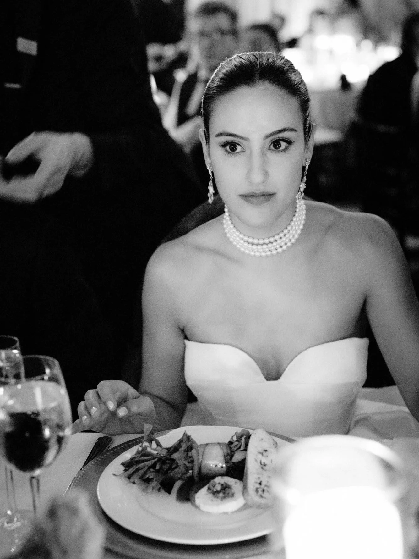 Black and white photo of a bride in pearls at a candlelit dinner table in Philadelphia, photographed by Jenny Fu.