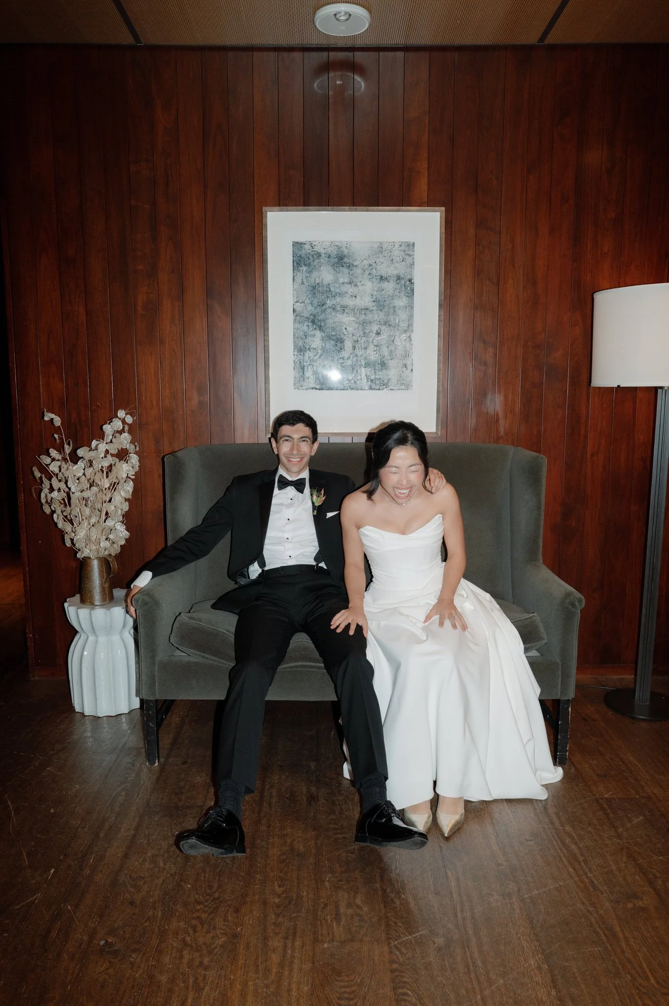 Newlyweds sharing a quiet laugh on a velvet settee between festivities at Blue Hill at Stone Barns, photographed by Jenny Fu.