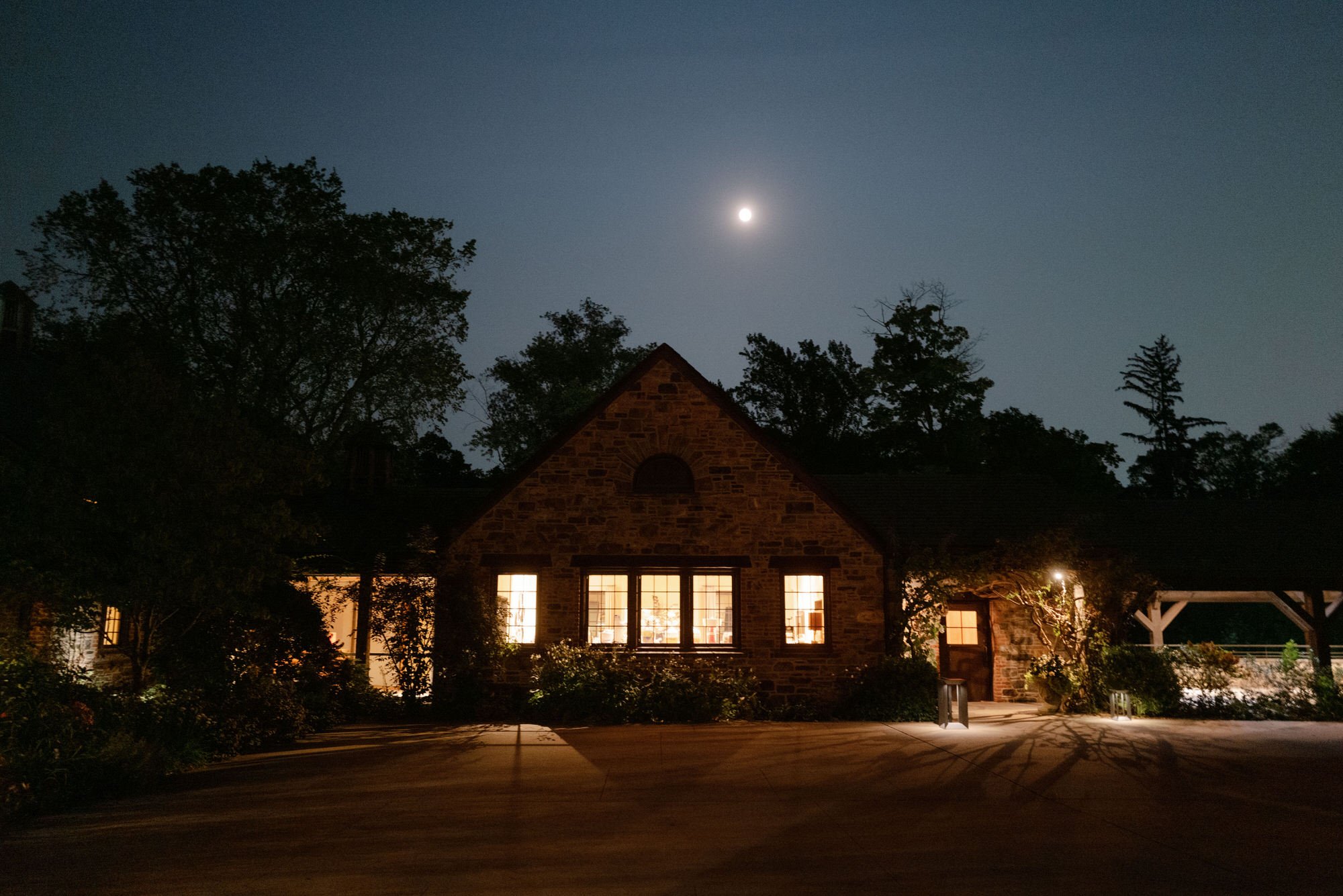 Moonlit exterior of the stone barn with warm windows glowing at Blue Hill at Stone Barns, photographed by Jenny Fu.