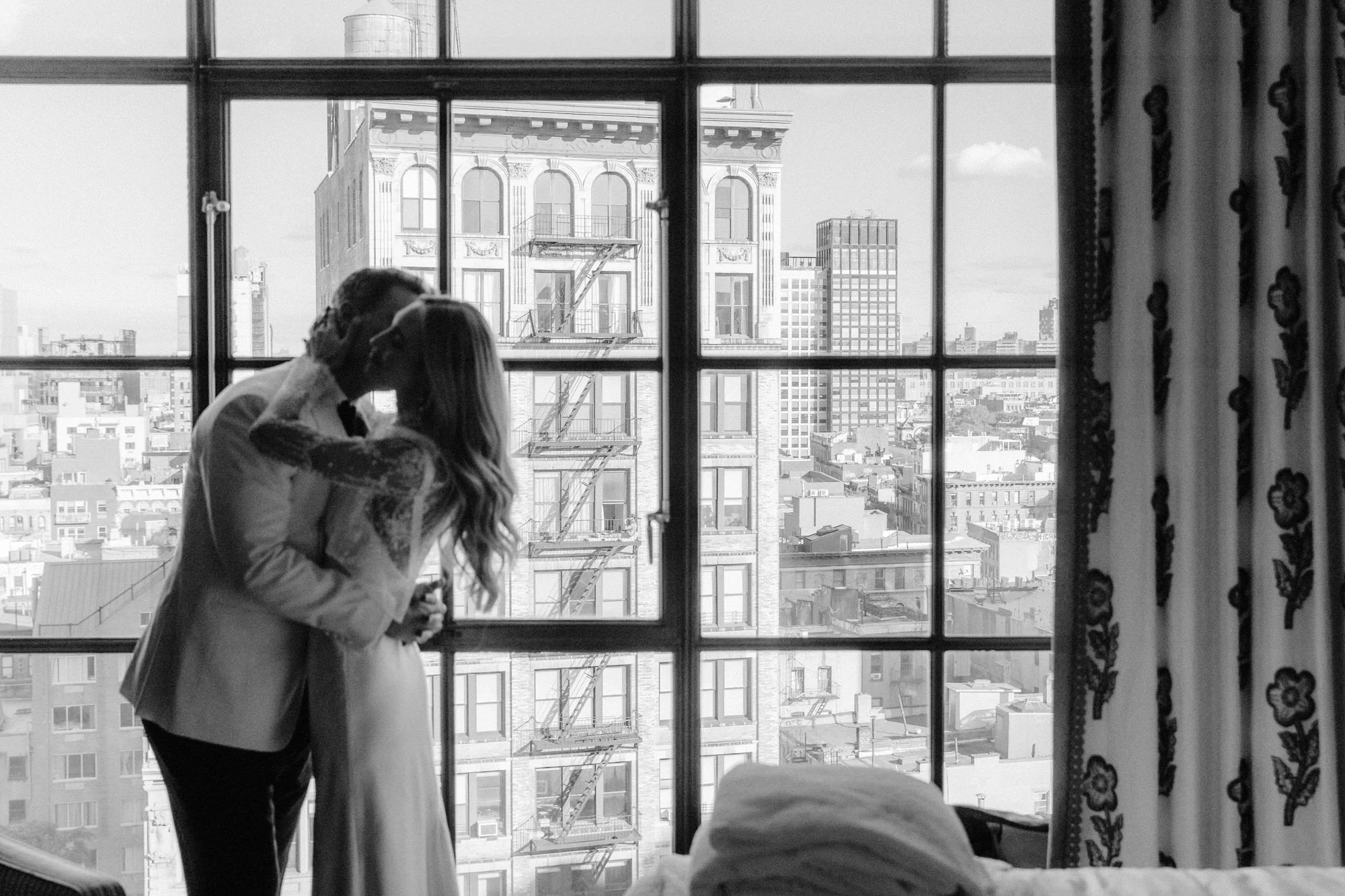 Bride and groom sharing a quiet kiss by the window overlooking downtown Manhattan at Crosby Street Hotel in Soho, photographed by Jenny Fu.
