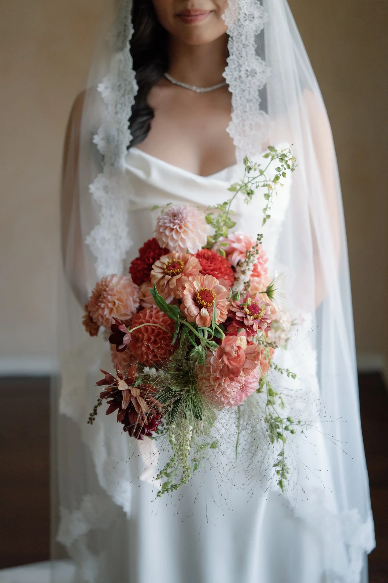 Bride holding a coral dahlia bouquet beneath a lace-edged veil at Blue Hill at Stone Barns, photographed by Jenny Fu.