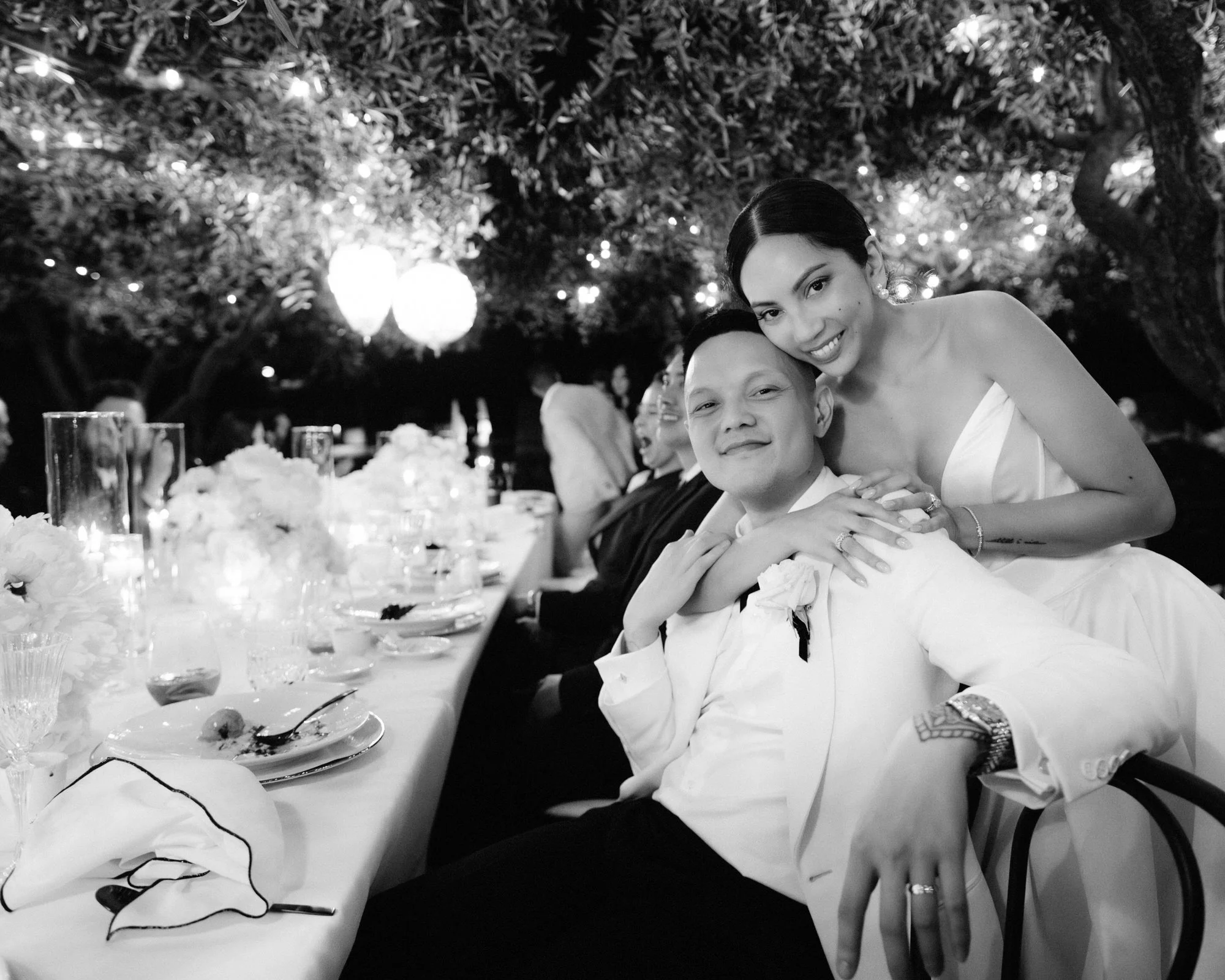 Bride and groom embracing during dinner beneath olive trees and twinkling lights at Caruso, A Belmond Hotel in Ravello, Italy, photographed by Jenny Fu.