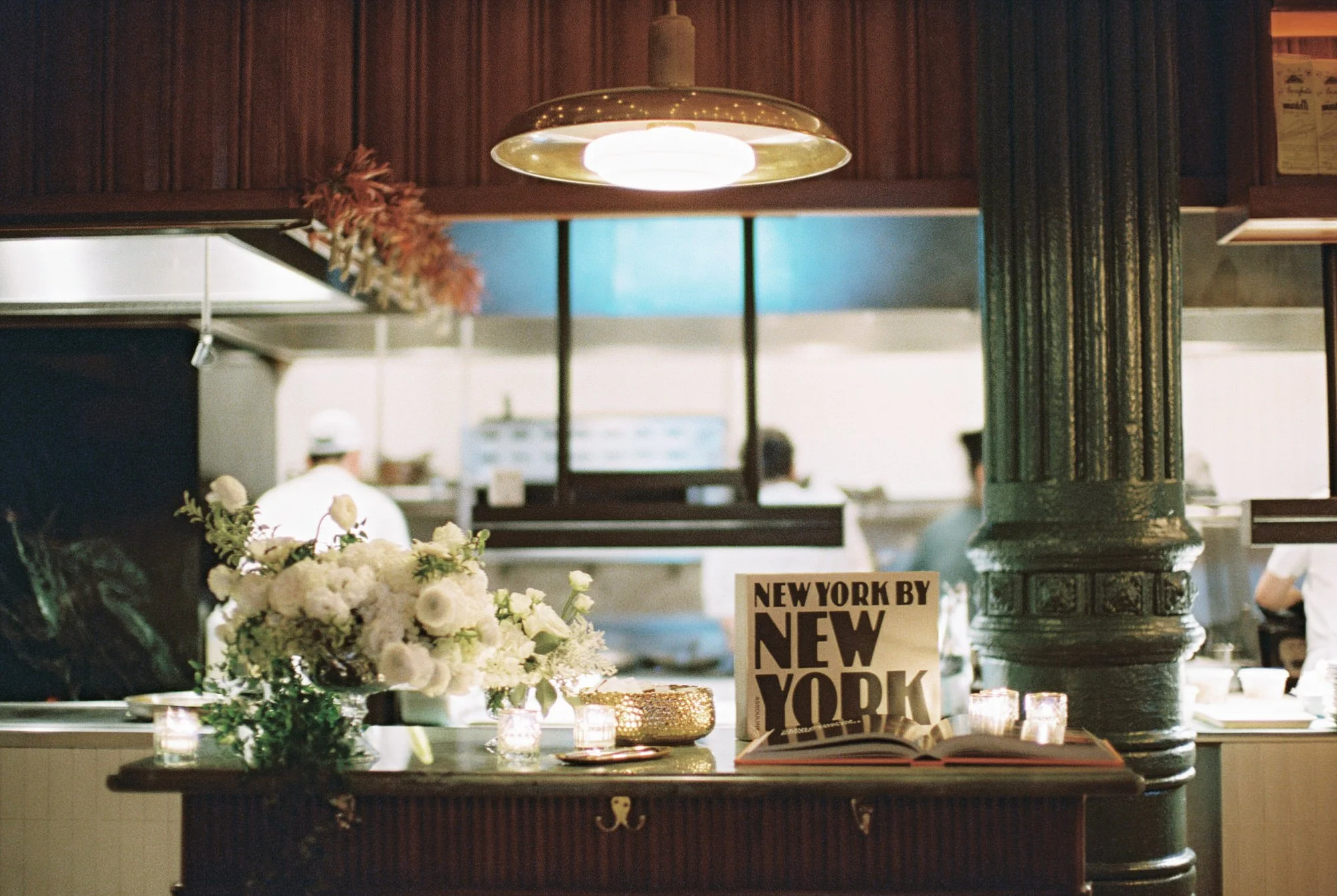 Chic display of florals and design books near the open kitchen at Torrisi in Manhattan, photographed by Jenny Fu.