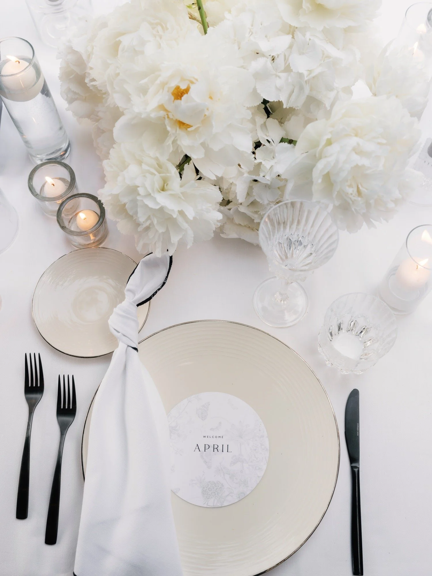 Refined dinner place setting with white peonies and candles on a linen table at Caruso, A Belmond Hotel in Ravello, Italy, photographed by Jenny Fu.