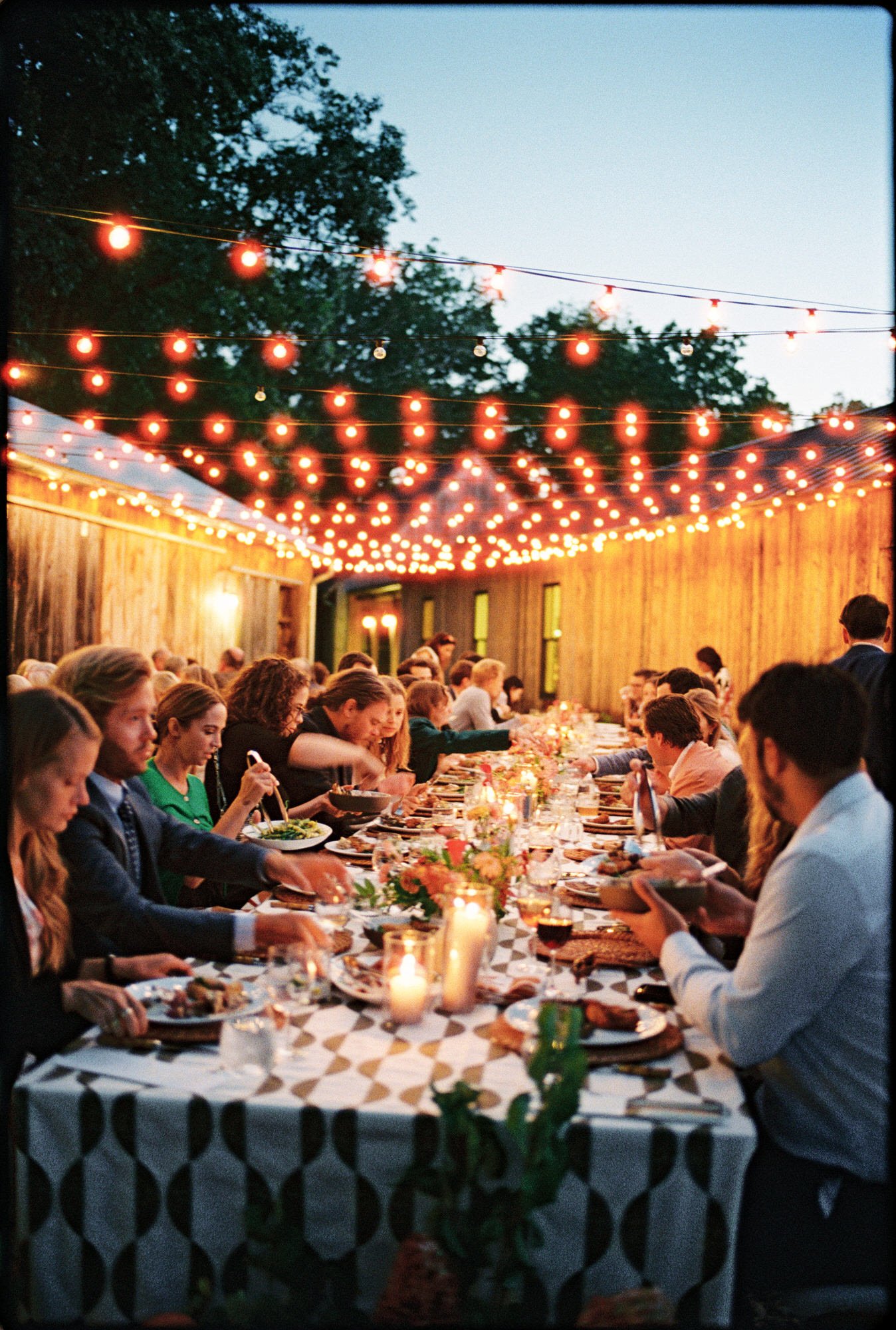 Guests enjoying a candlelit dinner under string lights at the welcome party at Troutbeck in Amenia, photographed by Jenny Fu.