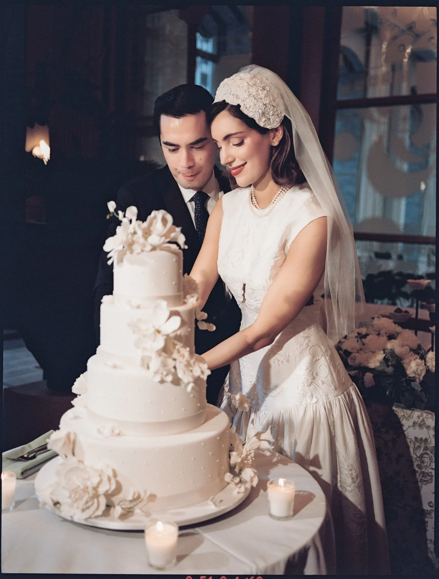 Bride and groom cutting their four-tier wedding cake by Ron Ben Israel with sugar flowers at the Waldorf Astoria New York, photographed by Jenny Fu.