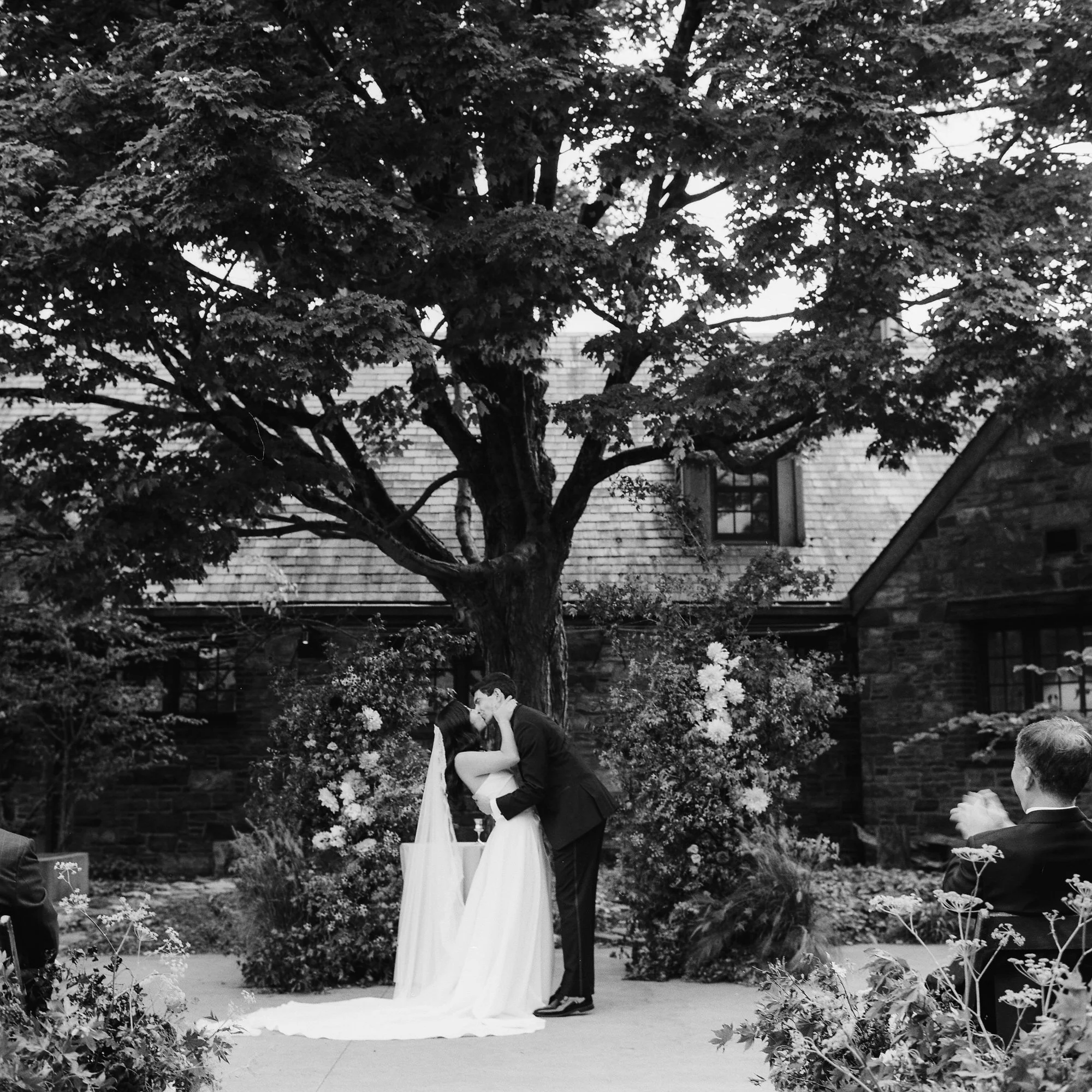 First kiss beneath the maple tree surrounded by garden florals in black and white at Blue Hill at Stone Barns, photographed by Jenny Fu.