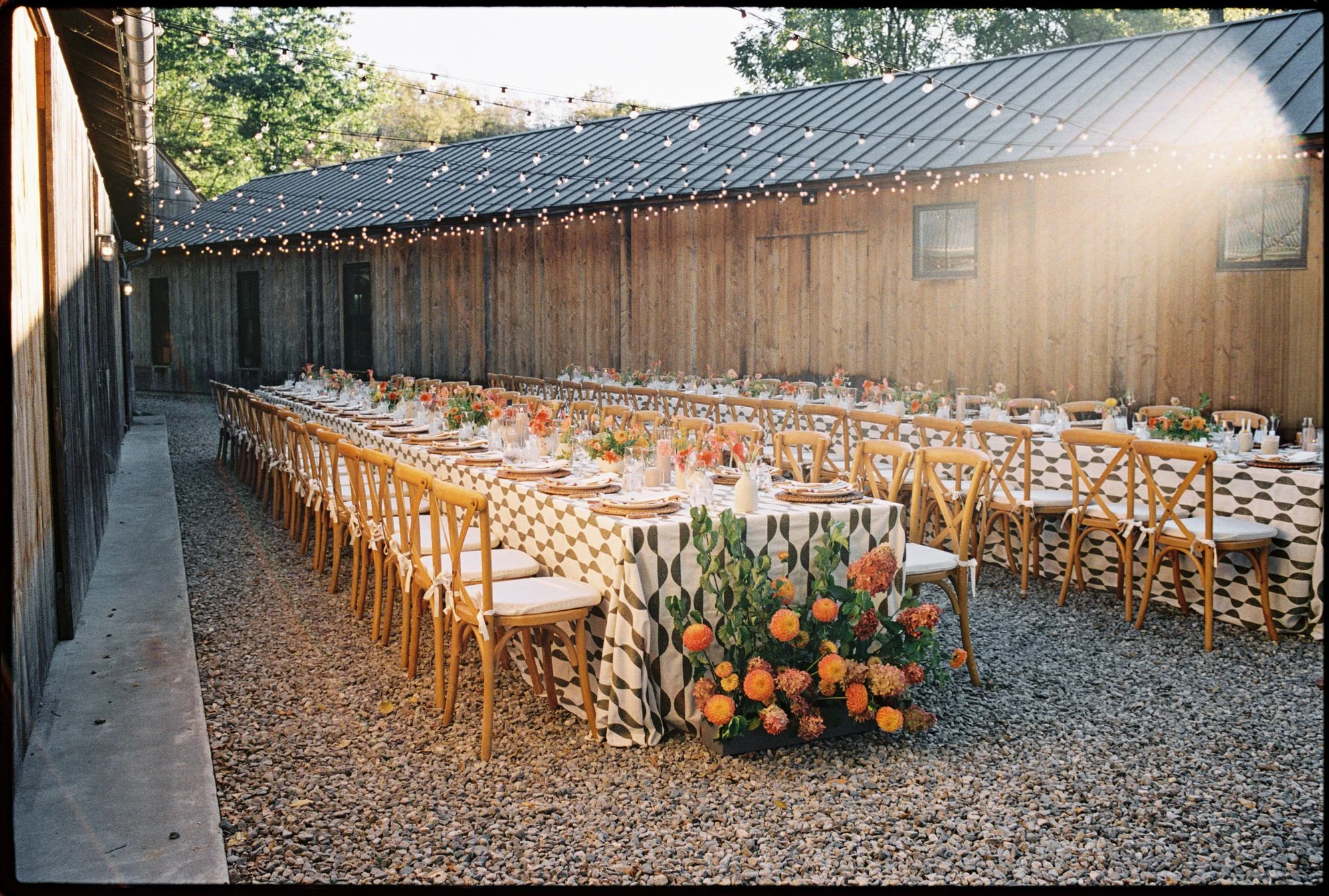 Outdoor welcome dinner setup with long floral-lined tables and string lights at Troutbeck in Amenia, photographed by Jenny Fu.