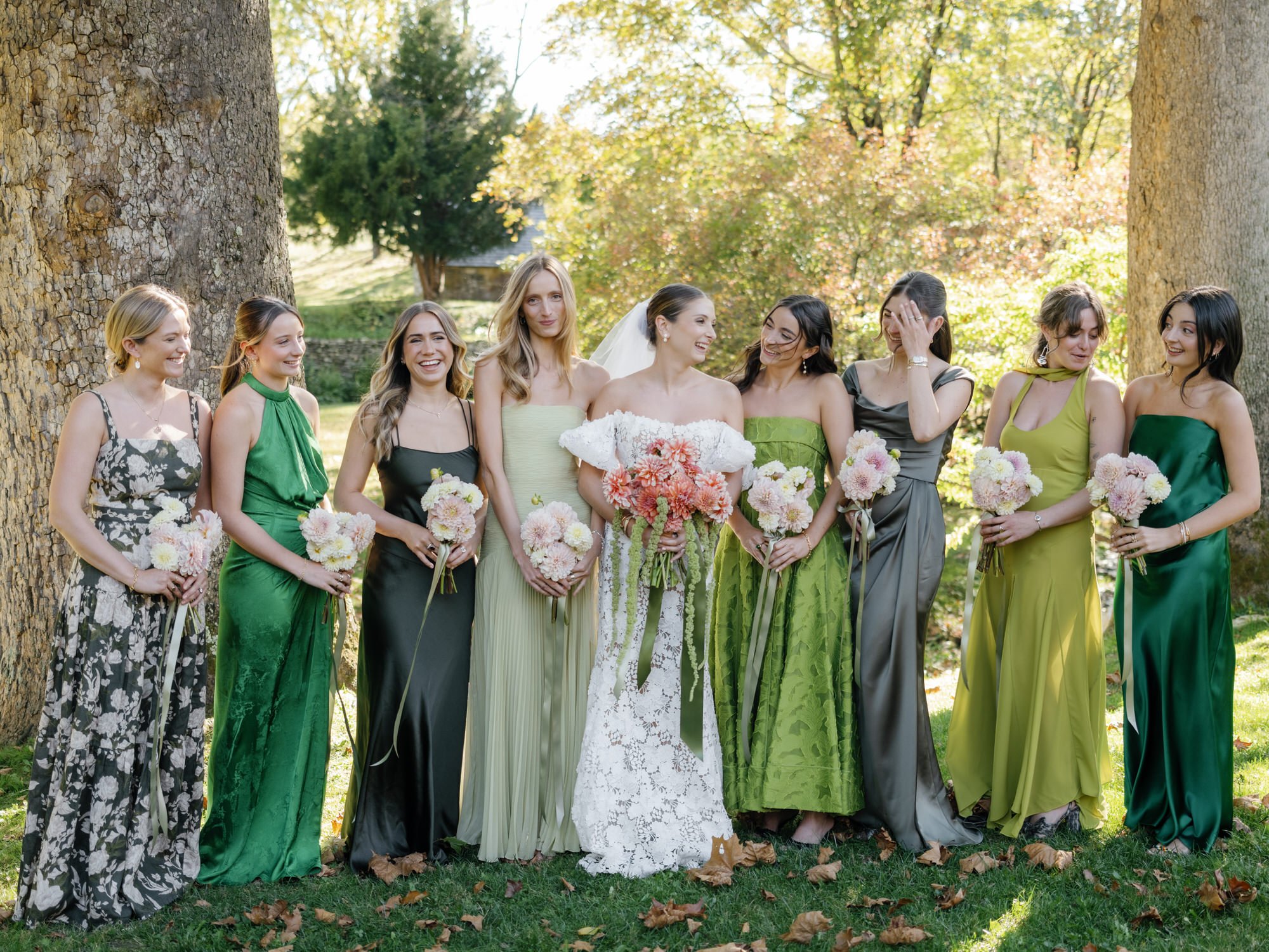 Bride laughing with her bridesmaids in mismatched green dresses and soft pink florals at Troutbeck in Amenia, photographed by Jenny Fu.