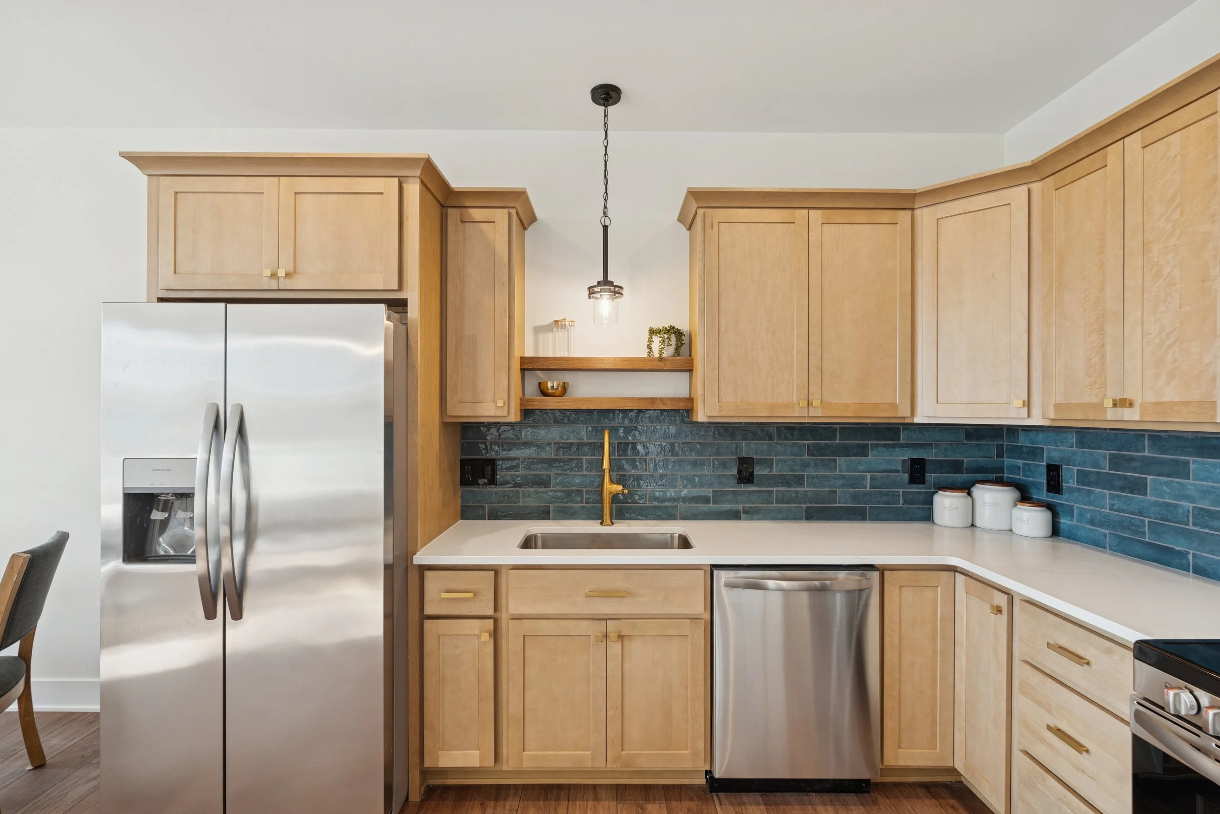 A dark gray single level condo wiht green lawn, white garage, small tree, at sunset in howell michigan