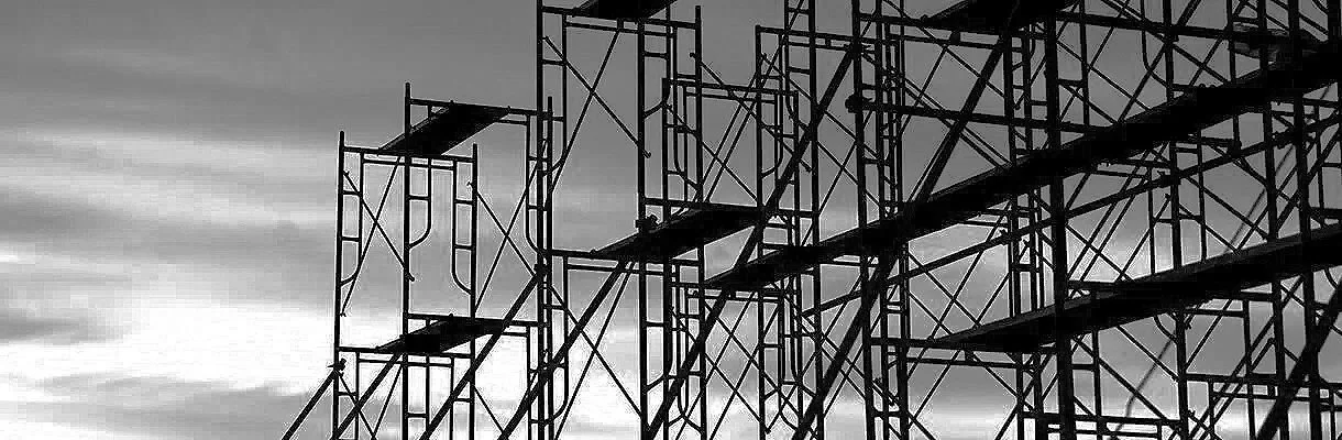 Black and white photo of a large metal scaffolding structure against a cloudy sky.