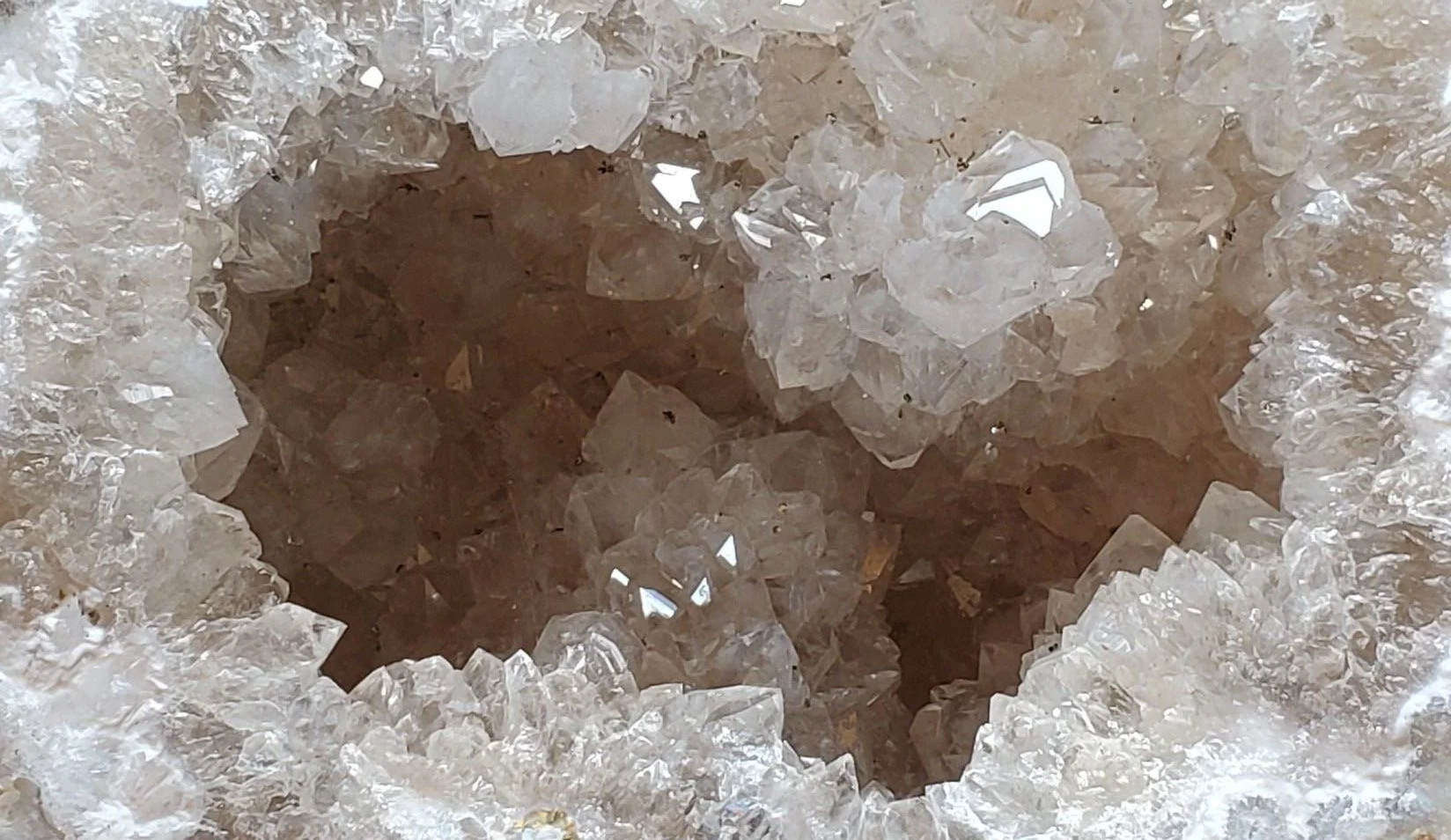 Close-up view of a crystal geode with a hollow cavity filled with clear quartz crystals.