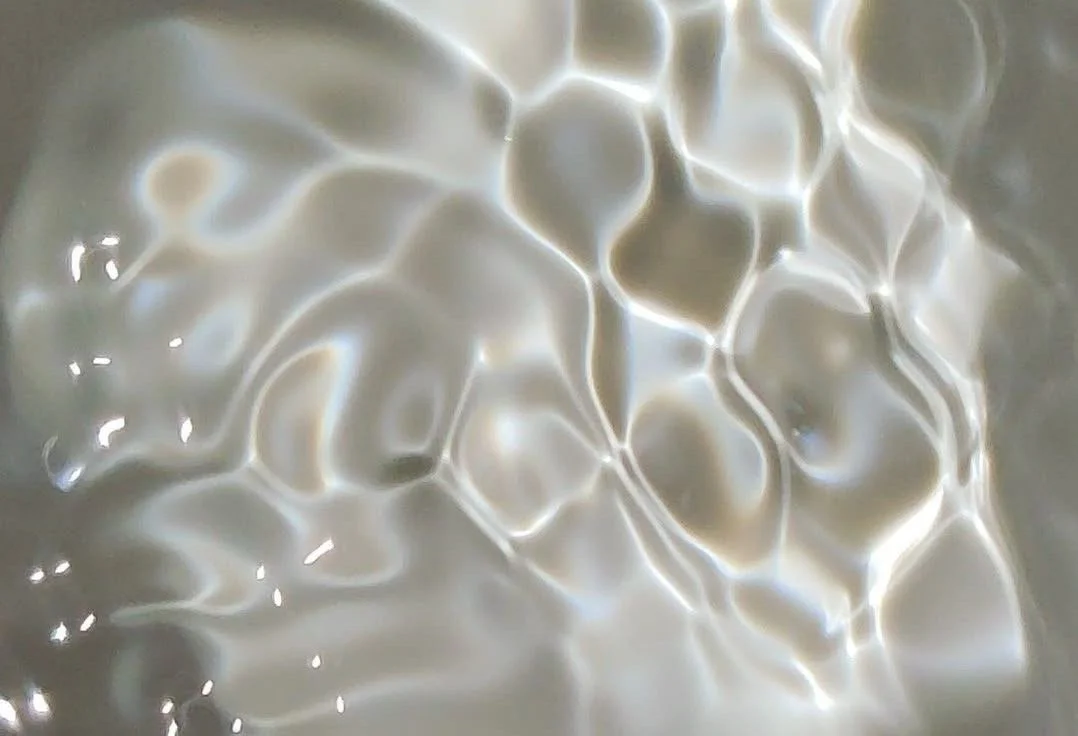 Close-up of a surface with irregular, interconnected shapes created by reflections and light.