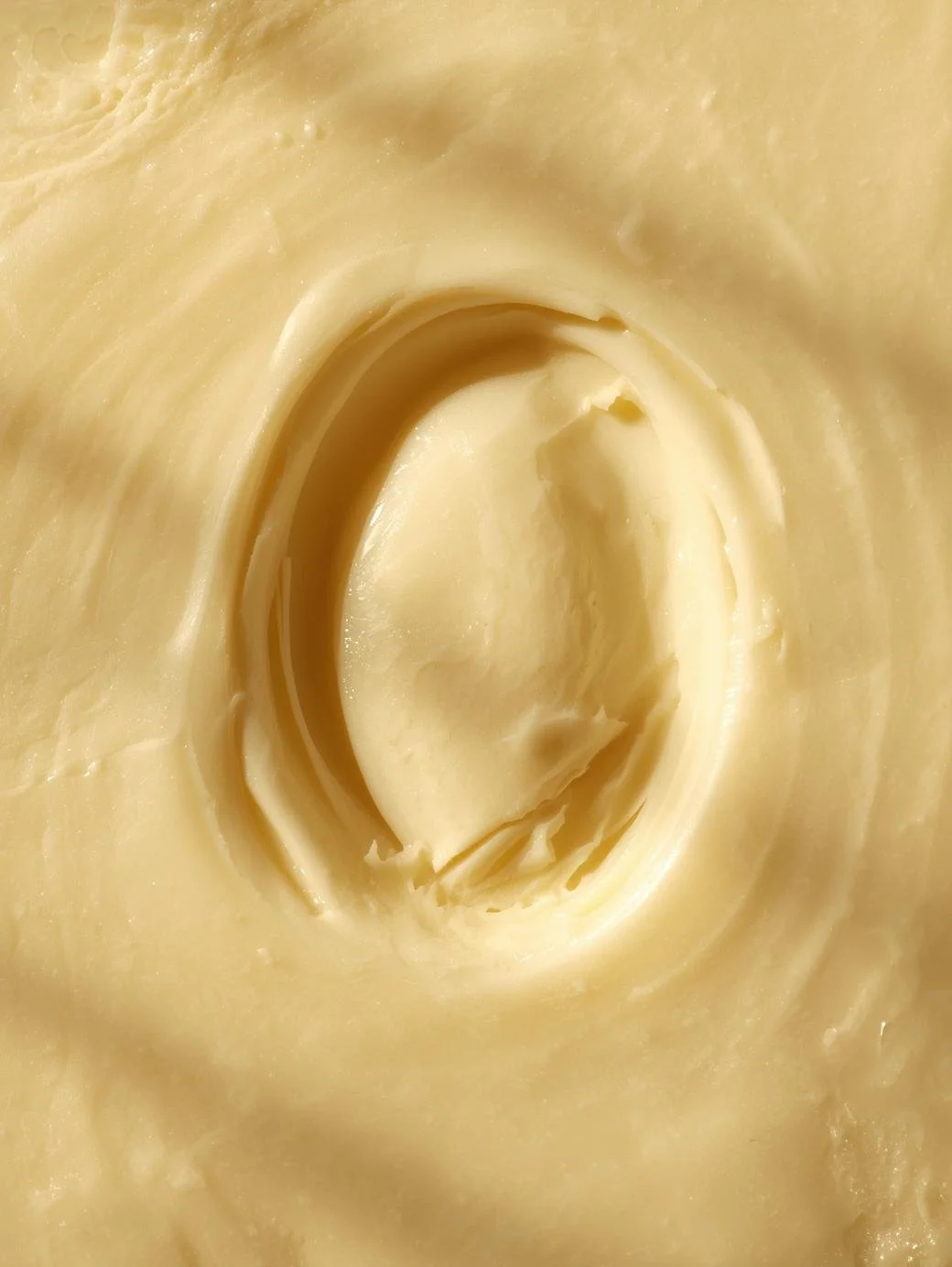 Close-up of creamy, yellow butter with a smooth texture and a swirl pattern.