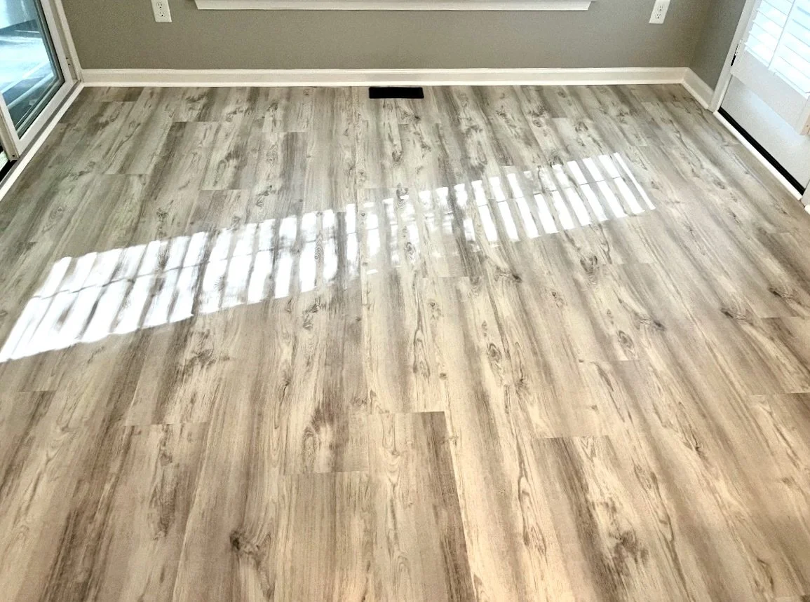 DMV DC, Maryland, Virginia flooring and carpet home repair, Clean hardwood floor reflecting sunlight from a nearby window in a room with light gray walls.