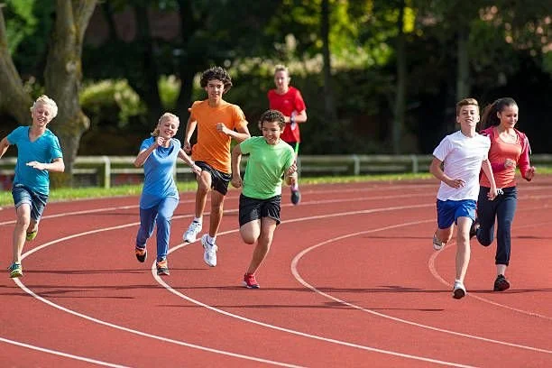 Group of children running on a track during daytime.