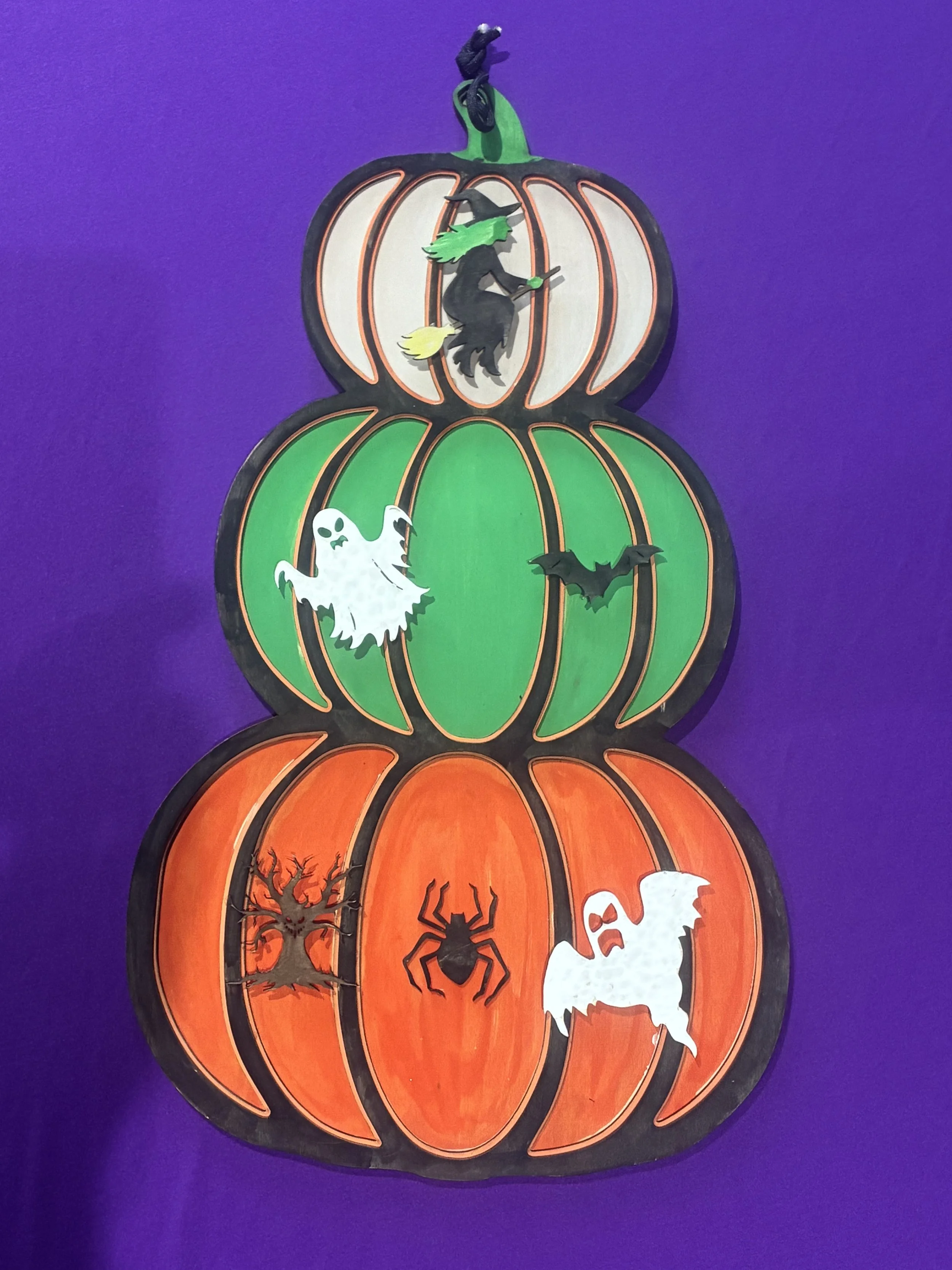 Stacked plastic pumpkin decorations with Halloween-themed illustrations and cutouts on a purple background.