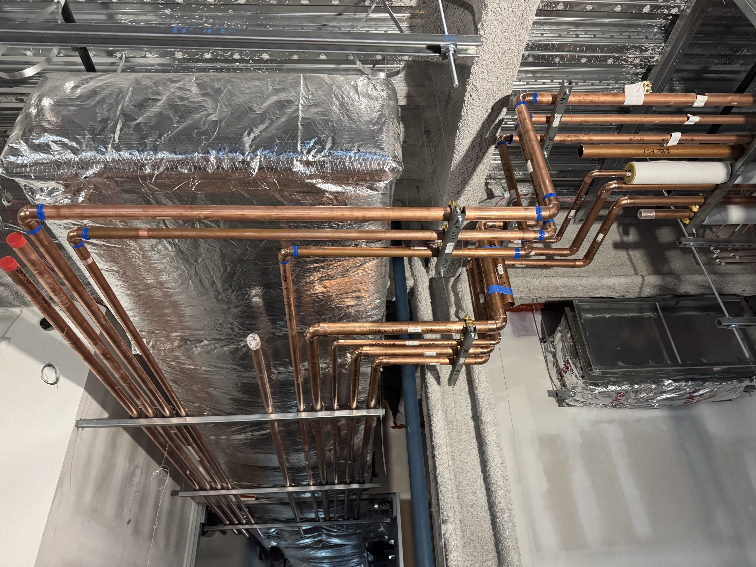 Construction site with copper pipes and insulation, building HVAC system.