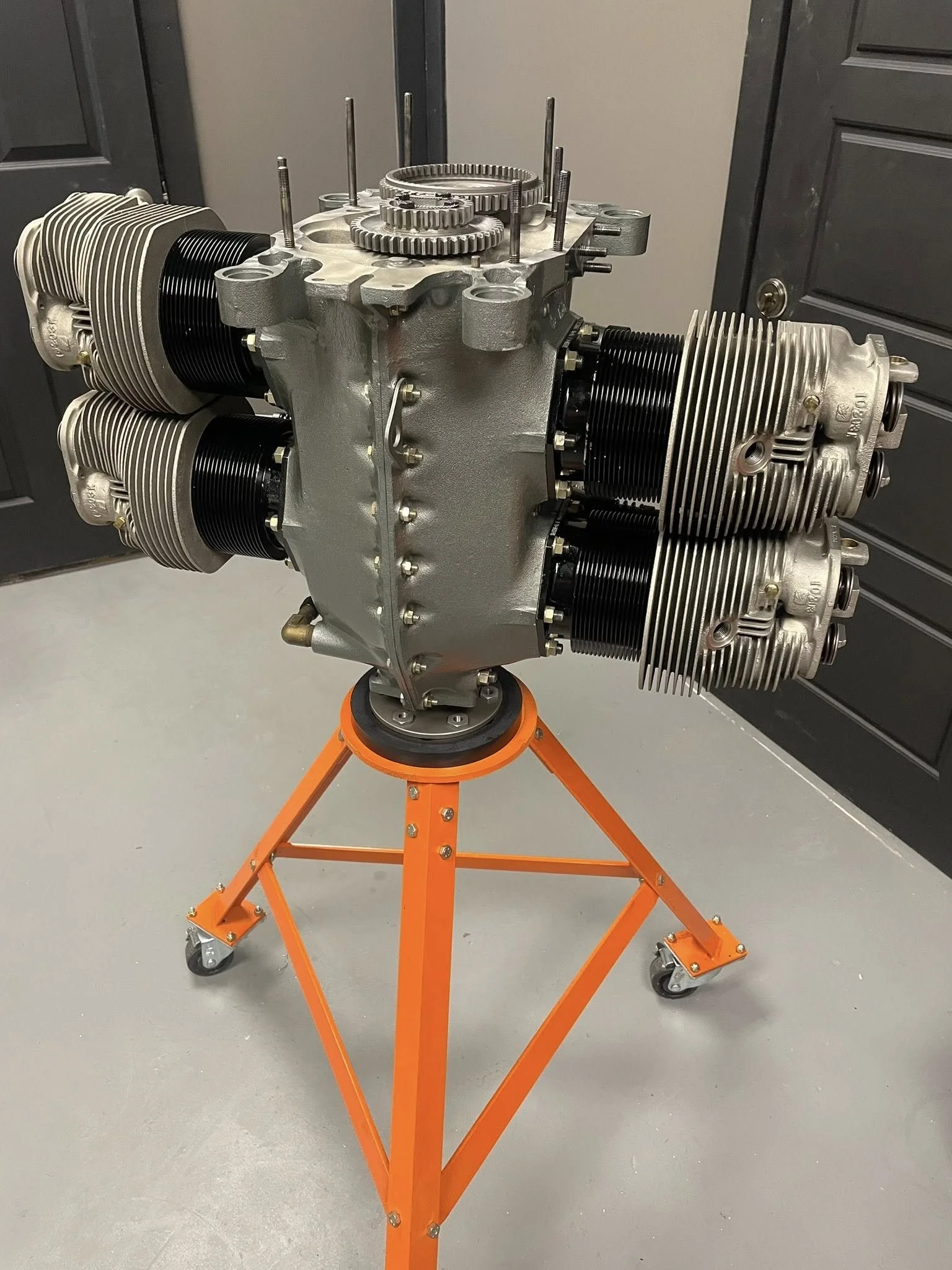 Aircraft jet engine mounted on an orange maintenance stand in a workshop.