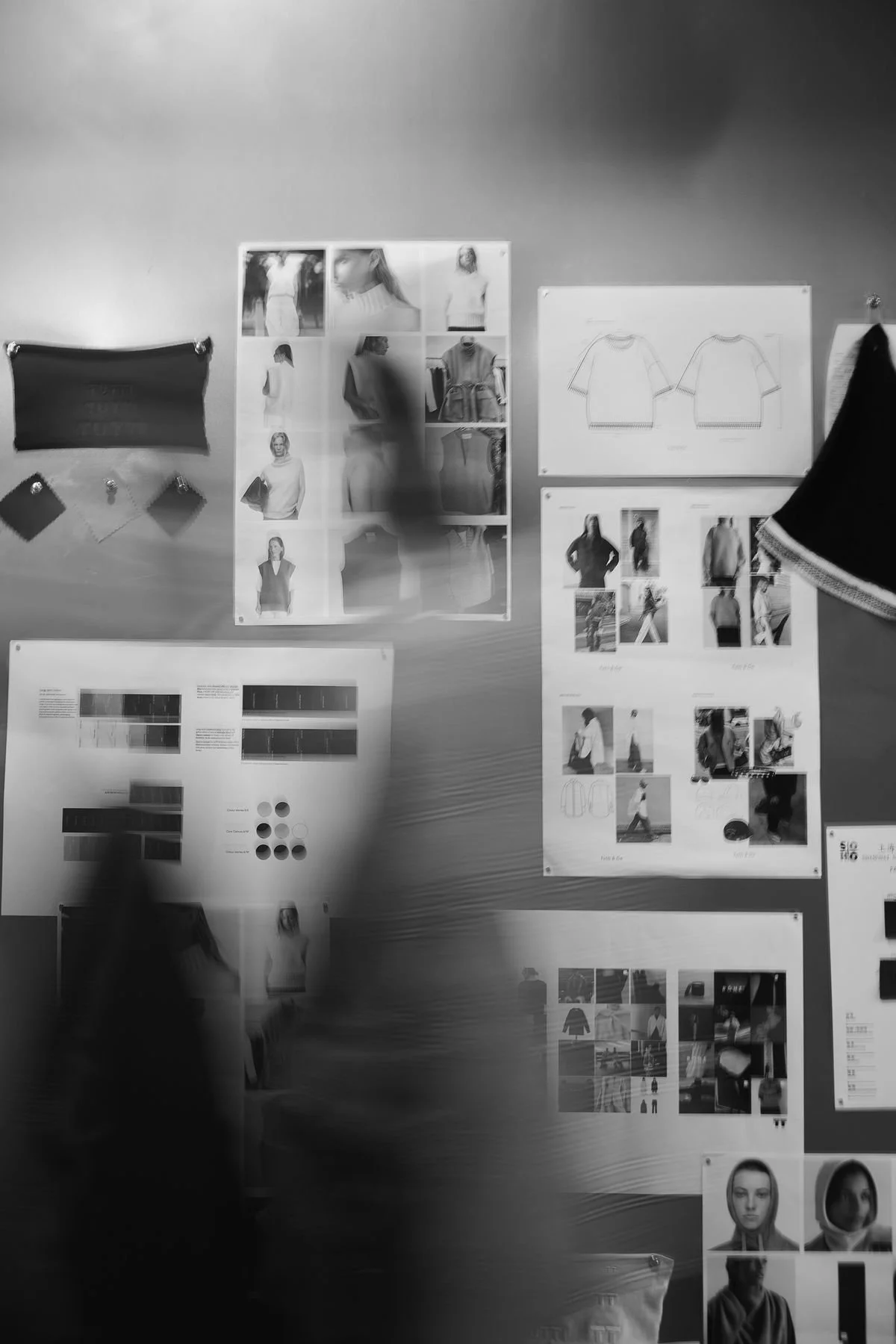 A classroom wall with fashion design sketches, photos of models, fabric swatches, and visual references for clothing patterns and styles.