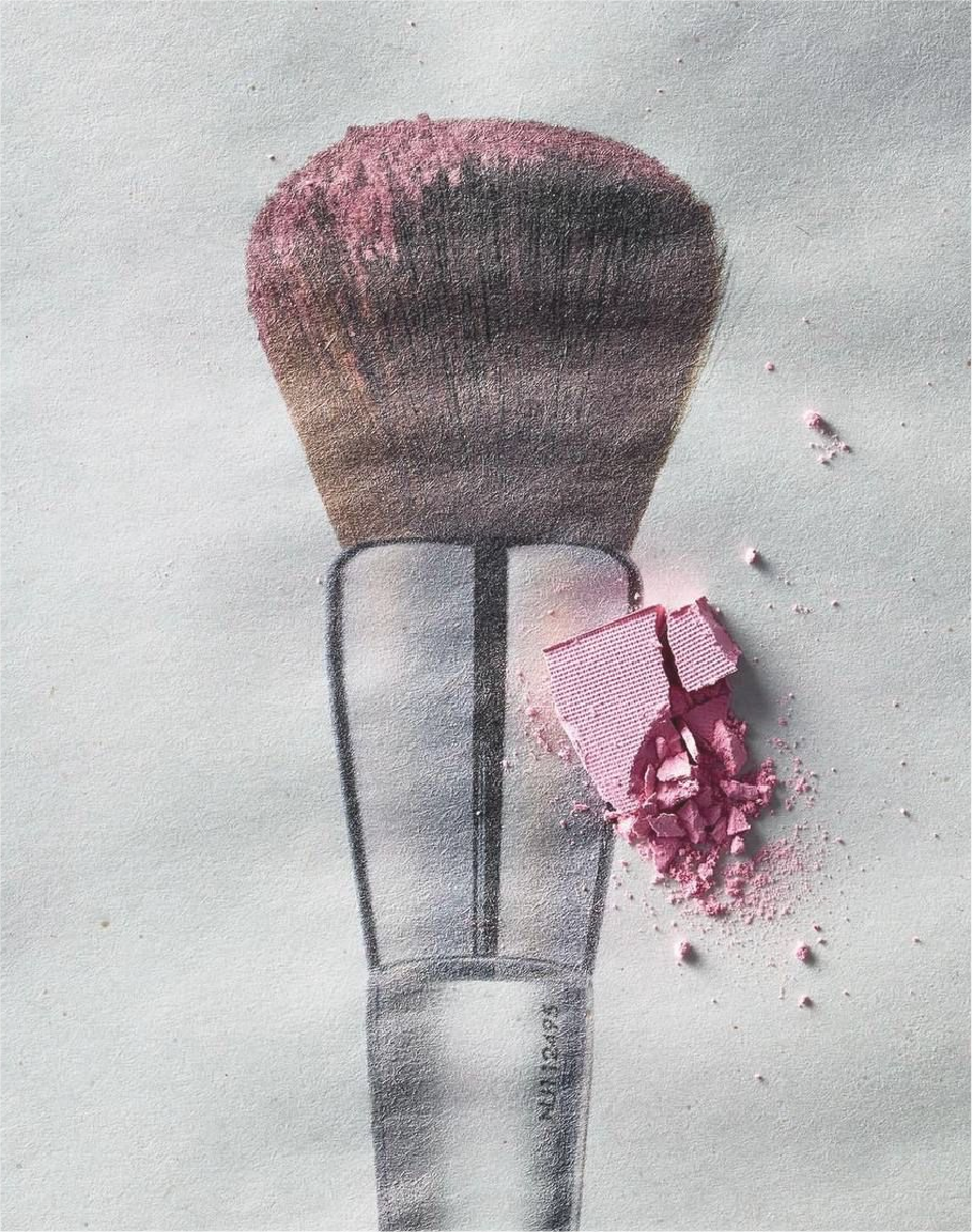 Painted makeup brush with pink blush powder spilled beside it on a white surface.