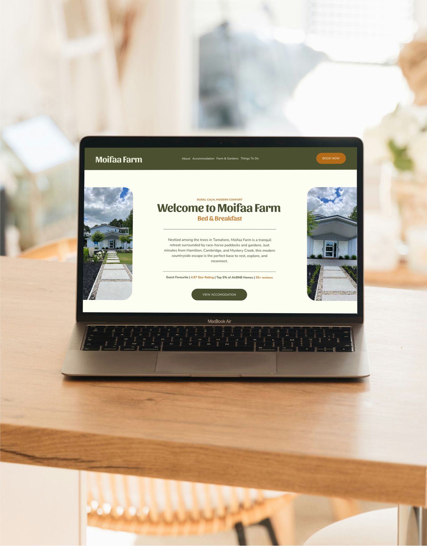 Laptop on a wooden table displaying a website for Moifaa Farm, showing a welcome message, images of the farm, and navigation options.